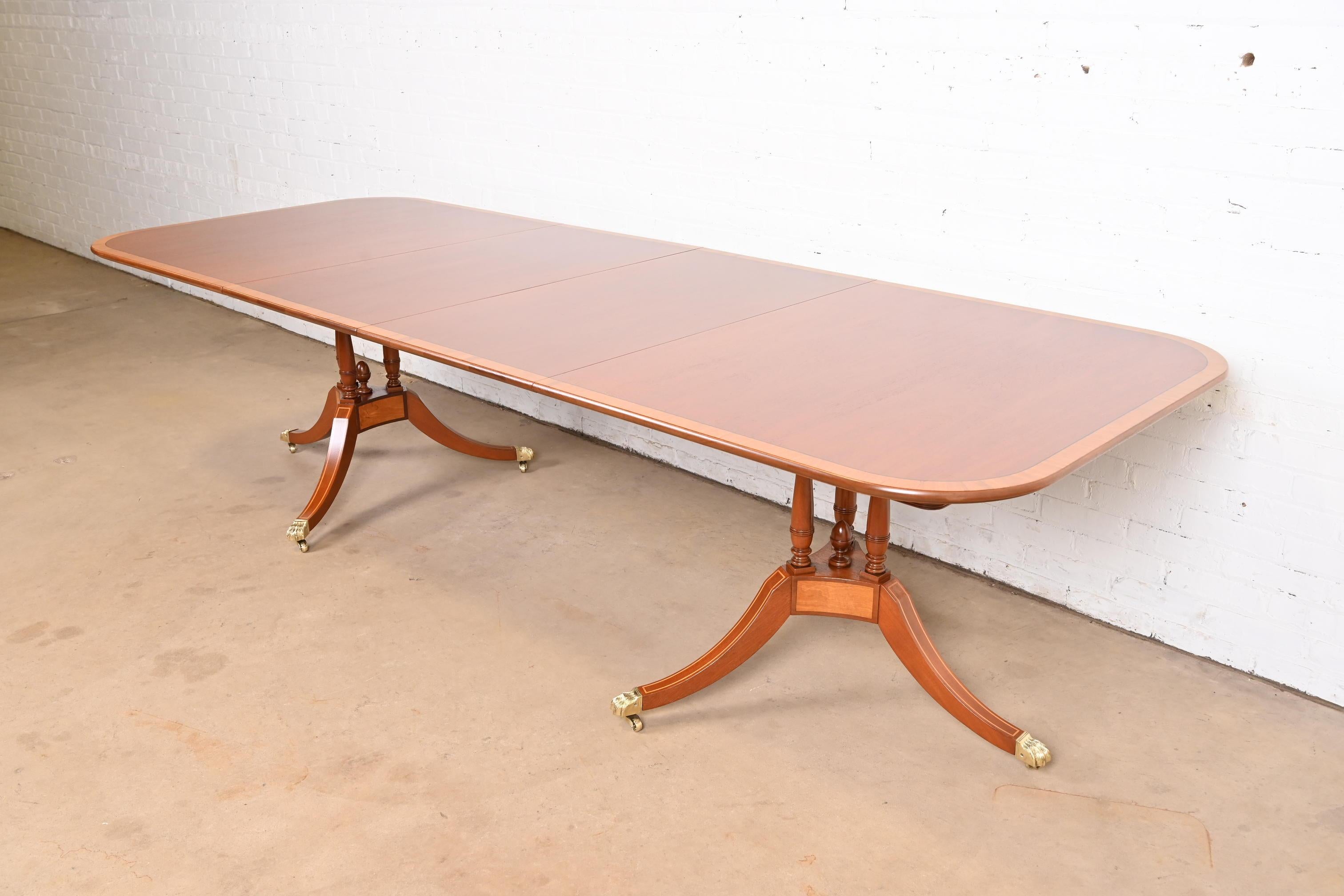 A gorgeous Georgian or Regency style double pedestal extension dining table

In the manner of Baker Furniture 

By Beacon Hill 

USA, Circa 1960s

Beautiful figured mahogany, with satinwood banding and inlay, carved solid mahogany pedestals, and