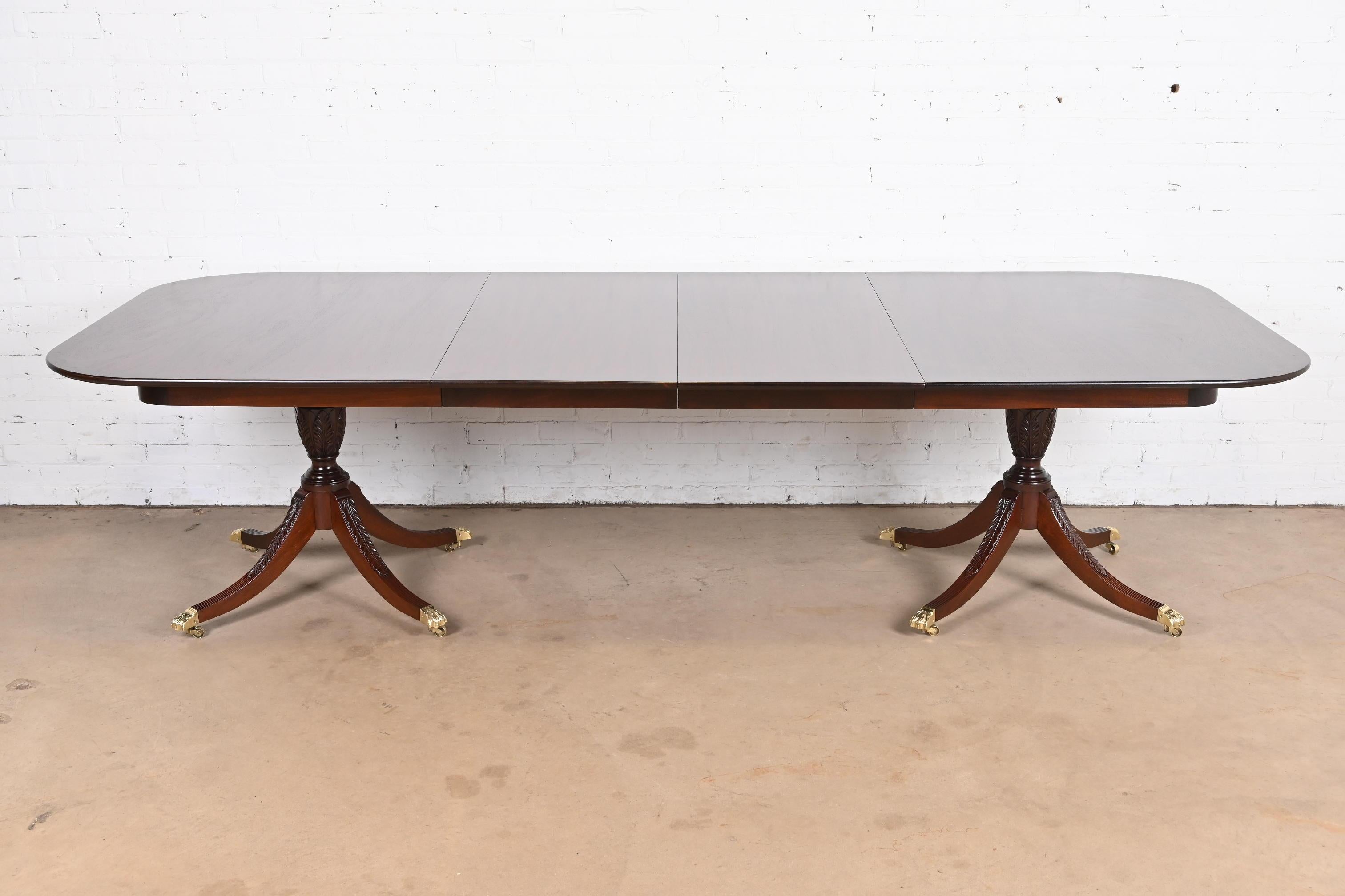 A gorgeous Georgian or Regency style double pedestal extension dining table

In the manner of Baker Furniture 

By Beacon Hill 

USA, Circa 1960s

Beautiful figured mahogany, with rosewood banding, carved solid mahogany pedestals, and brass-capped