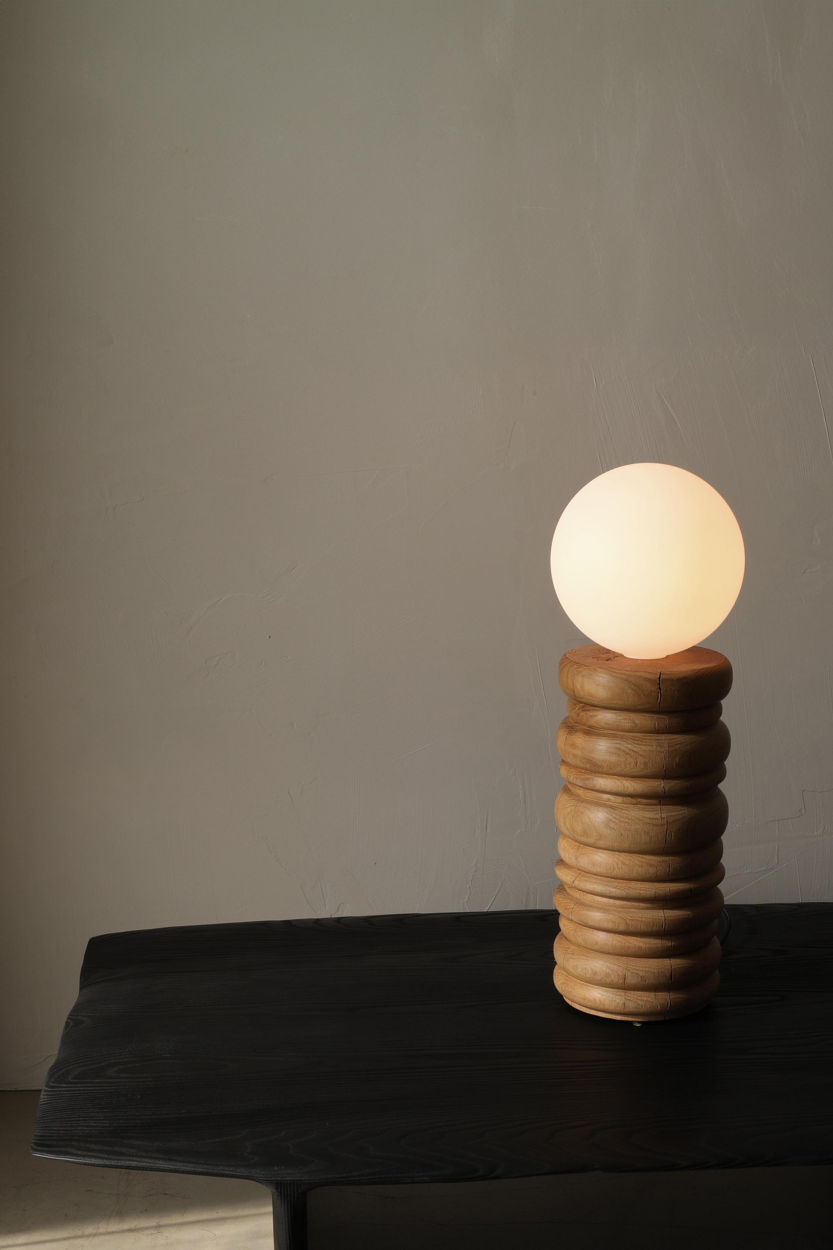 The Bead Lamp is a solid oak table lamp with a large frosted globe bulb. The lamp sits on three bronze feet and is switched on the cord with a dimmer.

BEAD - This collection is a blend of refinement and irregularity. The bases are carefully beaded