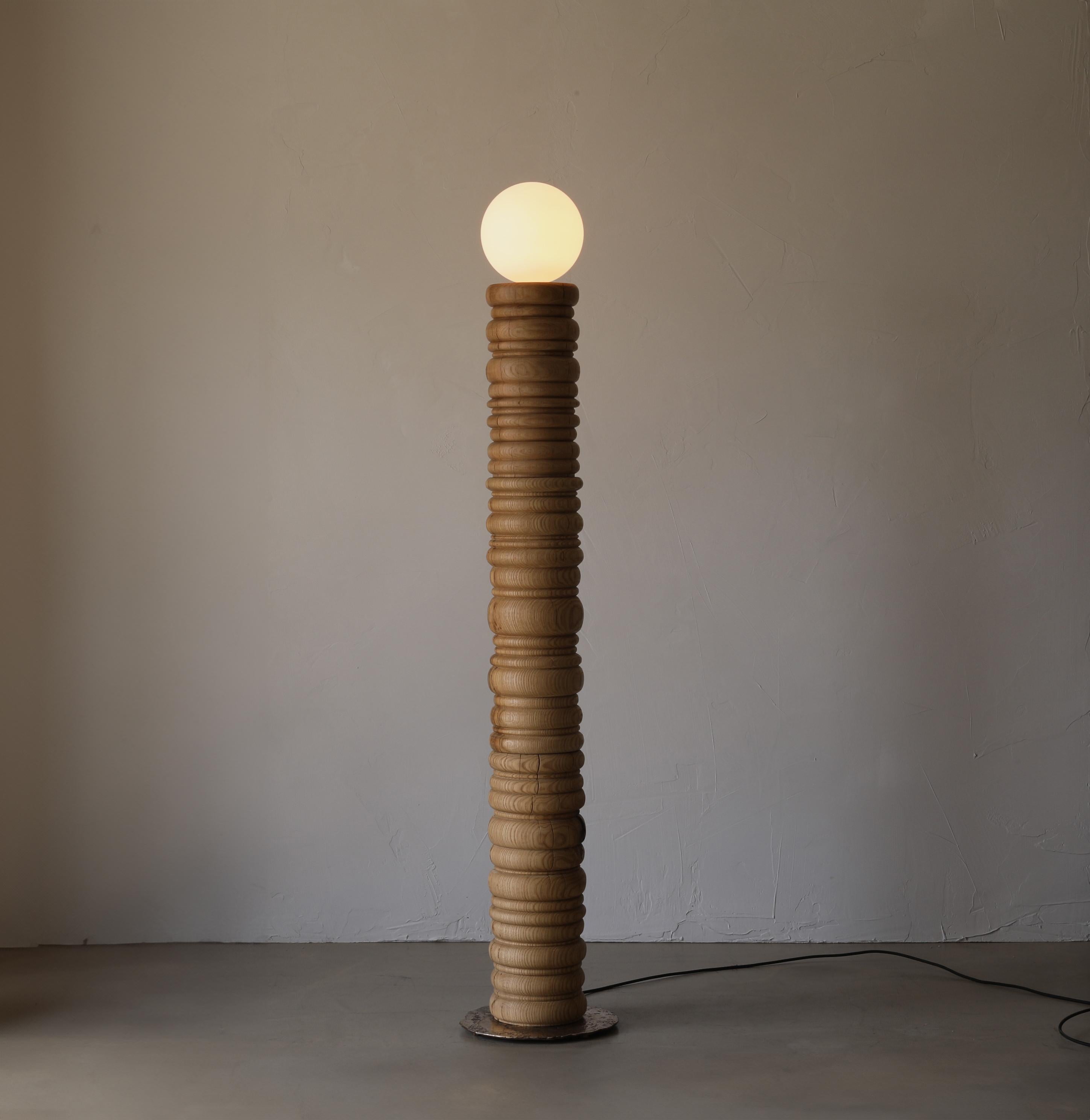 The Bead Lamp II is a solid oak standing lamp with a large frosted globe bulb. The lamp sits on a poured bronze plate and is switched on the cord with a dimmer.

BEAD - This collection is a blend of refinement and irregularity. The bases are