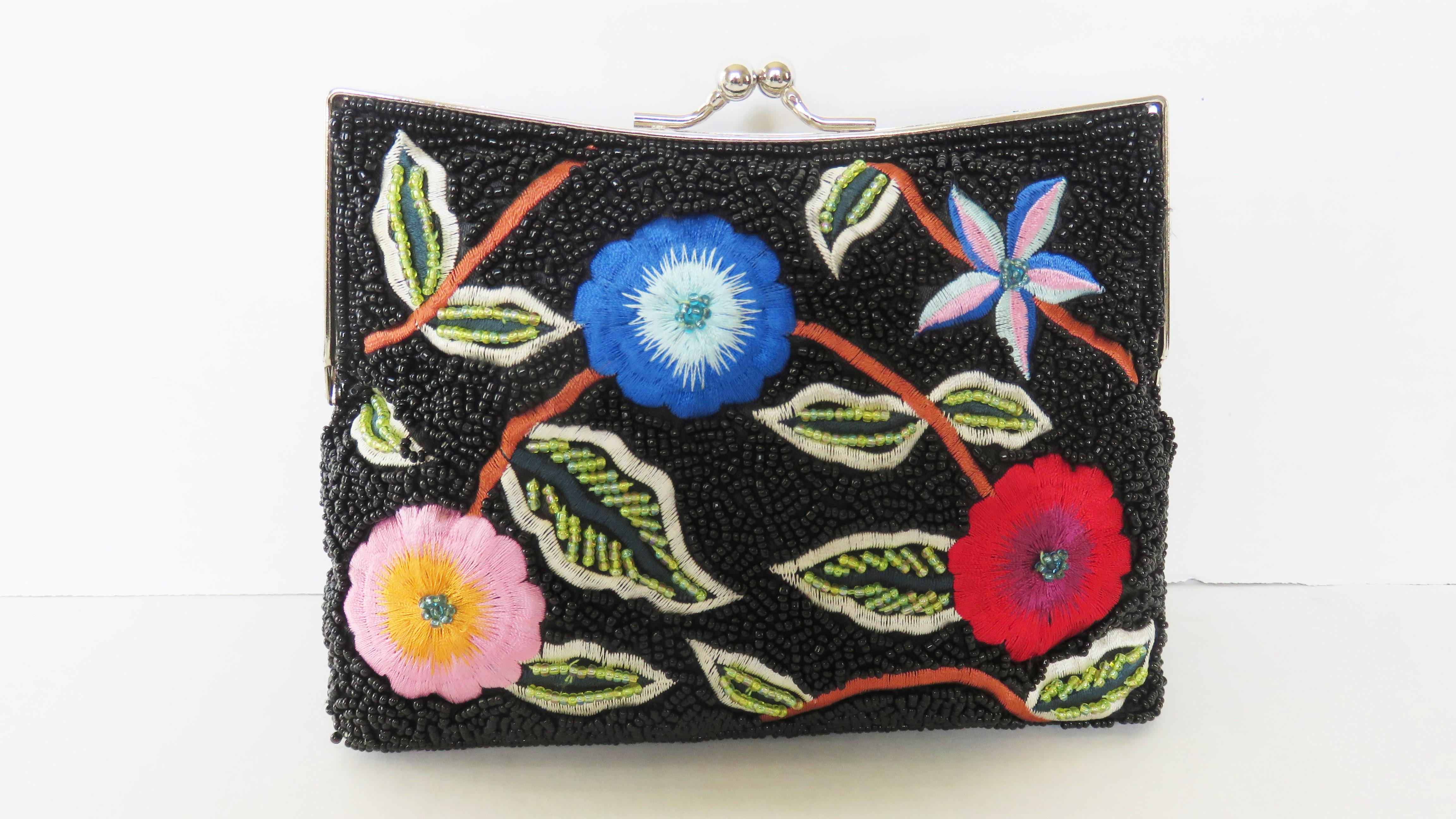 Una splendida pochette in vetro nero con perline e fiori colorati ricamati sia sul davanti che sul retro.  È dotata di una tracolla opzionale a catena argentata che si inserisce nella borsa con piccole cerniere, in modo da poterla usare come una