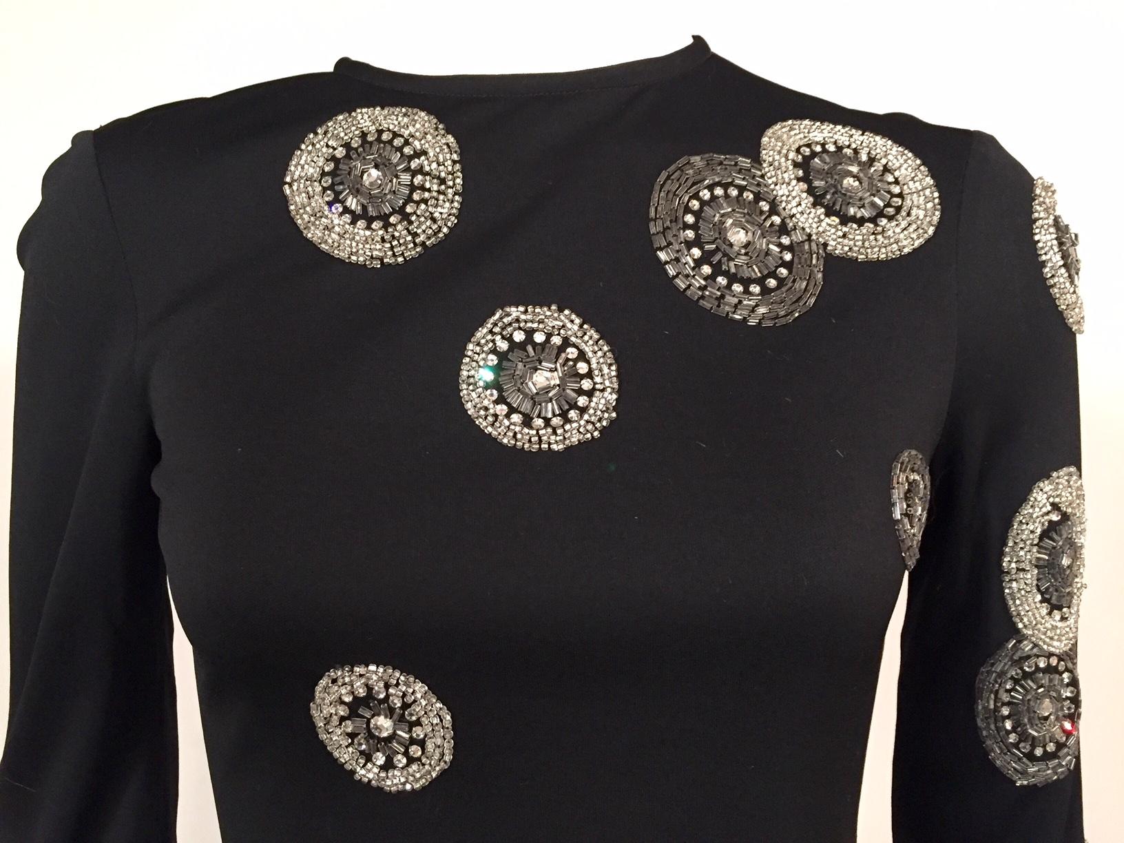 Black silk jersey is double layered for the front and back of this glamorous top. Silver bugle beads, caviar beads and glistening prong set rhinestones are used  to create large circular designs in an asymmetrical pattern on the left front, sleeve