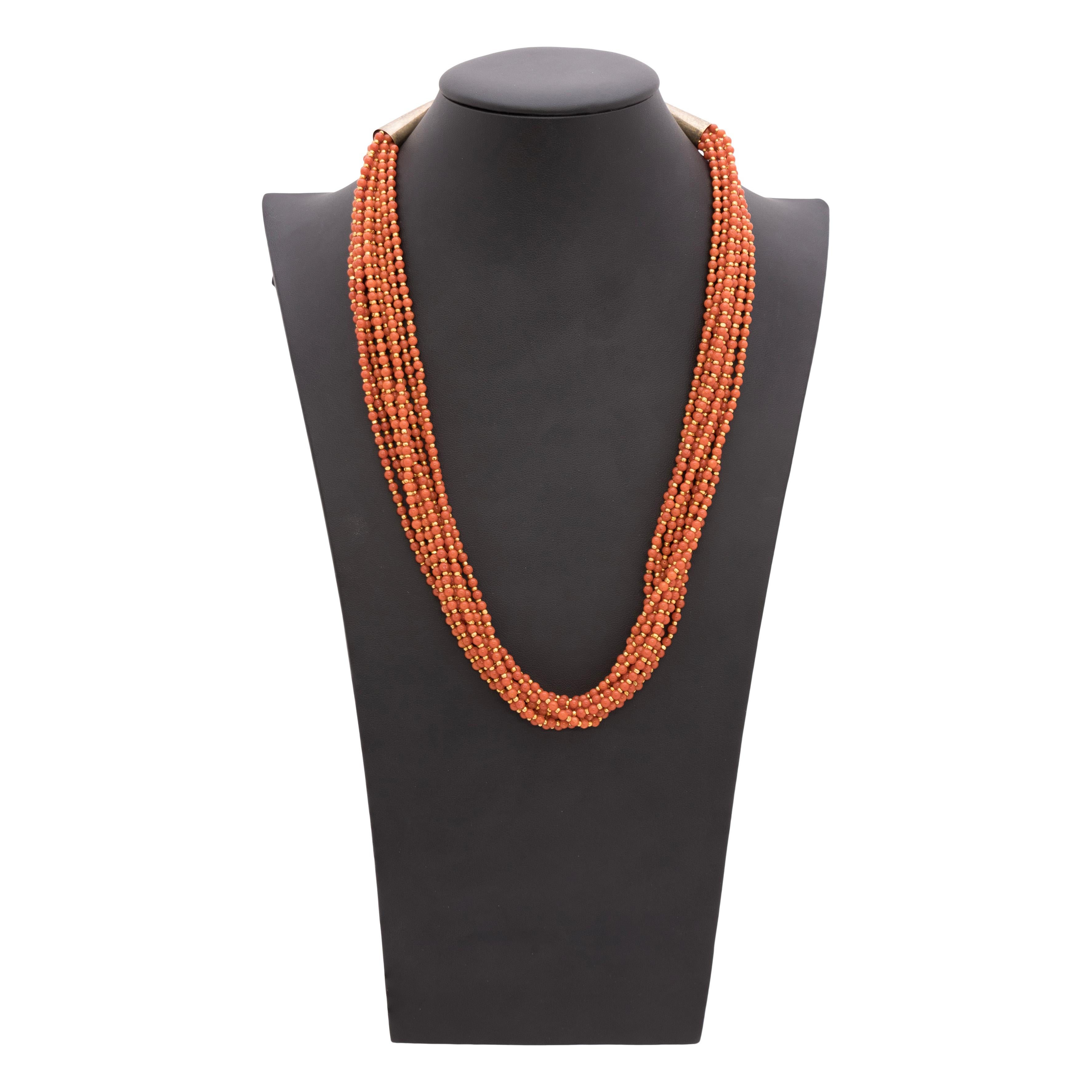 Collana di corallo con perline. Nove fili di perline con perle di corallo rotonde, intervallate da piccole perle di sterlina con sovrapposizione di oro 14K. Attaccati a chiusure tradizionali in argento sterling con sovrapposizione in oro 14k. Un