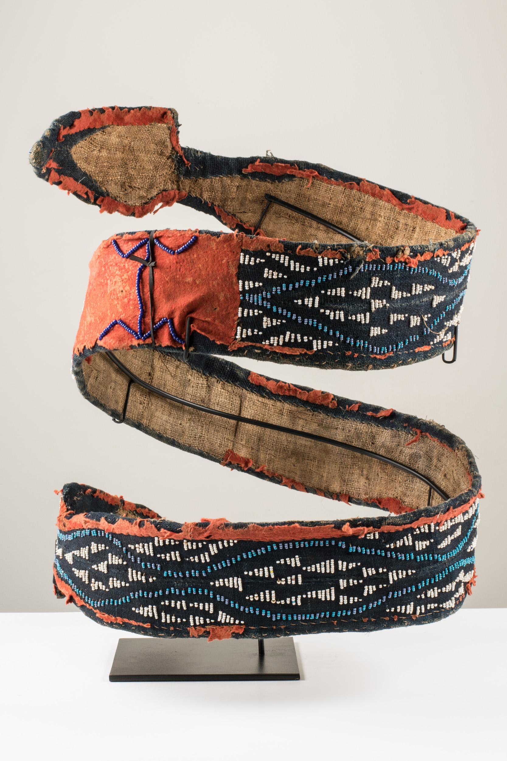 Le serpent à deux têtes est le symbole du royaume de Bamum. À l'origine, le roi était la seule personne à porter la ceinture constituée d'une bande de raphia tissée recouverte de tissu et de perles. Après l'arrivée des Allemands, les représentants