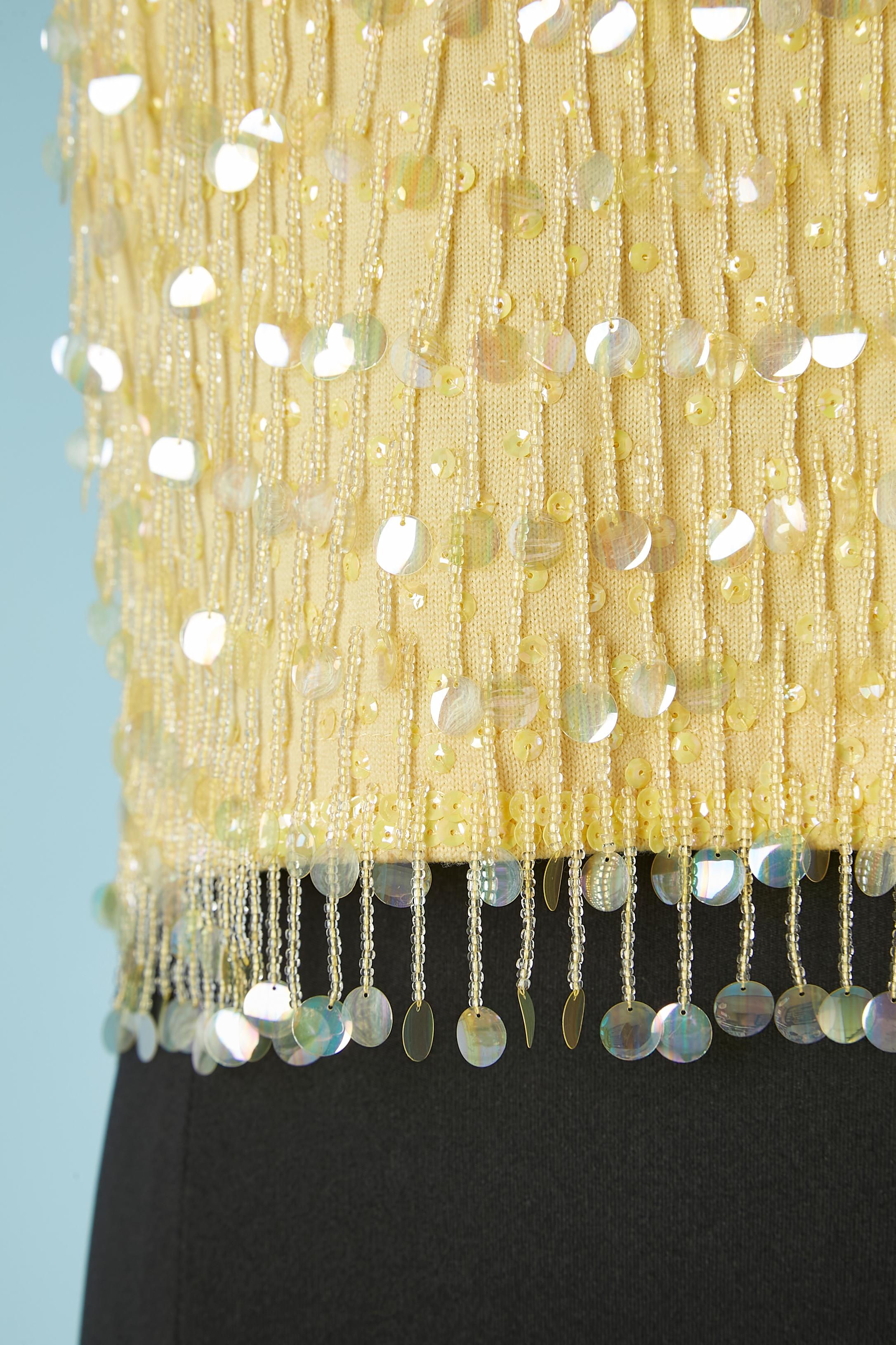 Haut sans manches à franges et paillettes sur base de tricot jaune (probablement de la laine). Doublure en acétate ou en rayonne. Fermeture à glissière au milieu du dos + crochet et œillet. 
TAILLE S.I.M. 