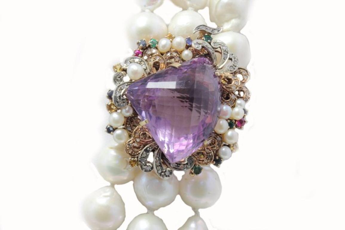 Classic and charming beaded multi strands necklace, embellished with a clasp composed of little pearls, sapphires, emeralds, rubies and diamonds that's surrounding  a shiny amethyst. All is mounted in 9 Kt rose gold and silver.
Tot Weight 361.1