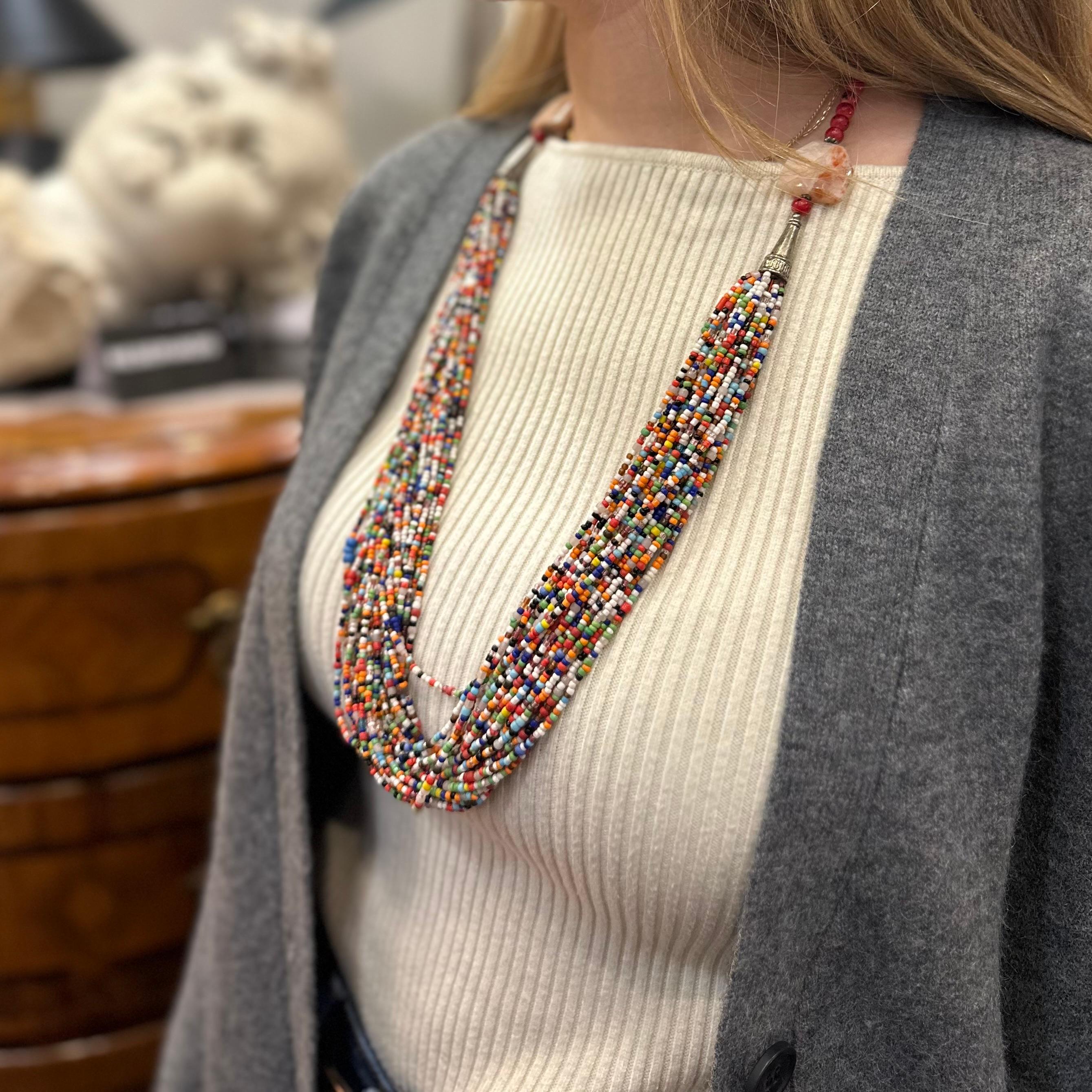 Hermosa y  collar muy Divertido con un diseño llamativo y colorido. Está formado por varias filas de cuentas, que se extienden desde dos piedras naturales y dos cuentas plateadas más grandes en la parte superior, justo donde empieza la parte que va