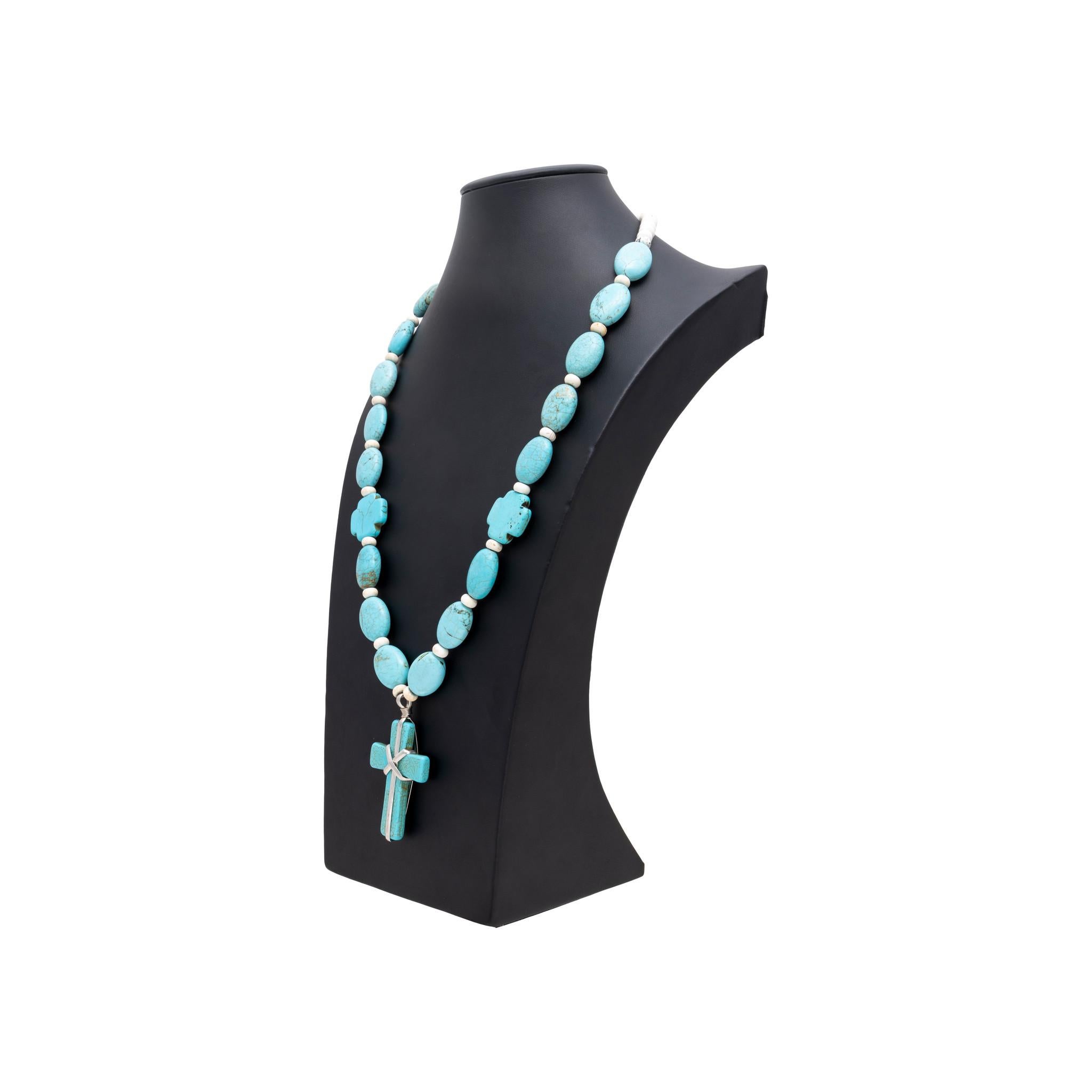 Native American Nacajo Indian turquoise beaded necklace. Featuring one large sterling wrapped cross pendant attached to beaded chain. Beads are also made of turquois and oblong shaped. Each turquoise bead is interspersed with small white beads. Two