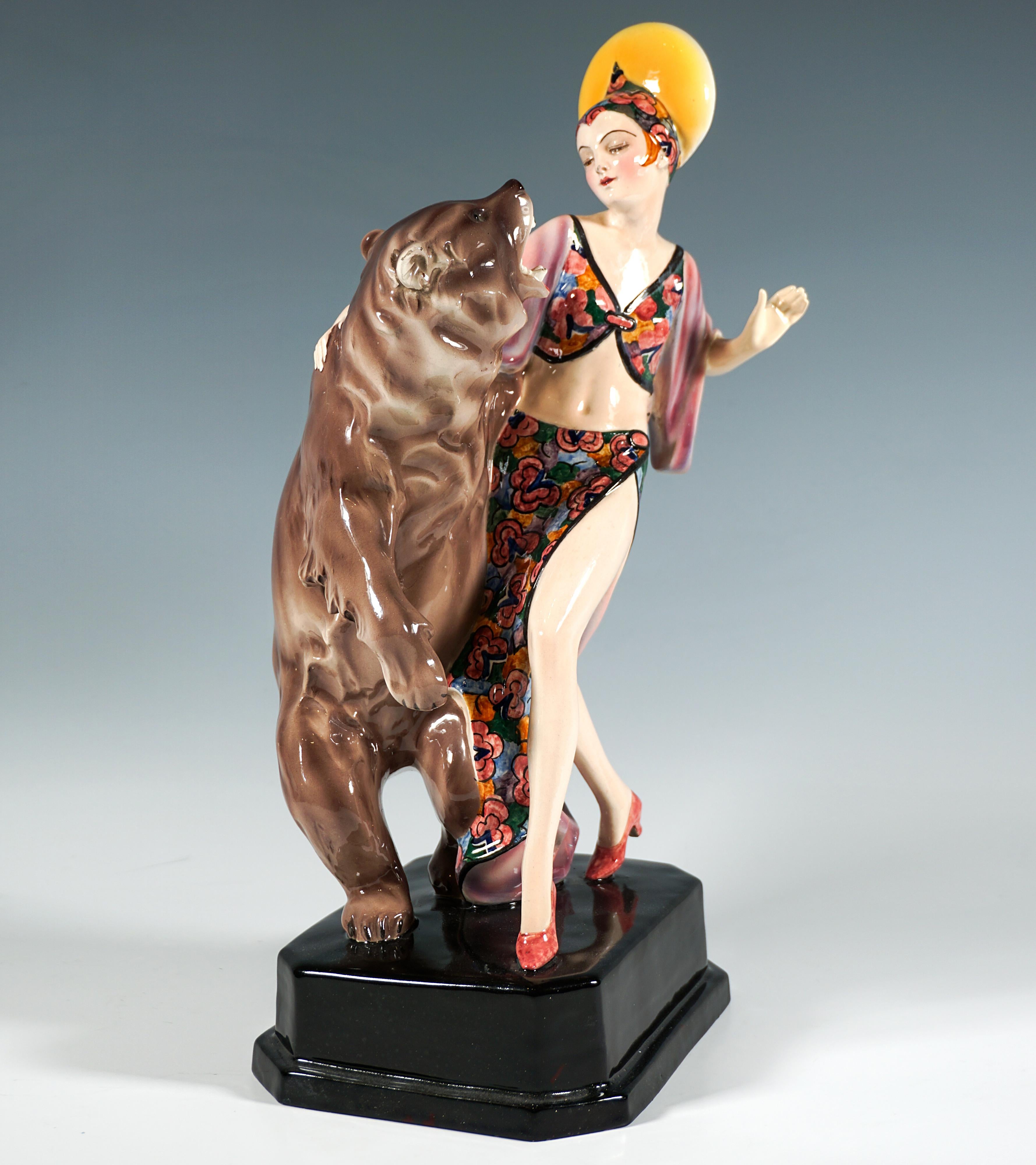 Very rare and exceptional Marcell Goldscheider ceramic figurine group:
Dainty dancer in a long, tight, high-slit skirt with coloured floral decoration, matching belly-free bolero jacket with wide sleeves and headdress with disc-shaped trimming,