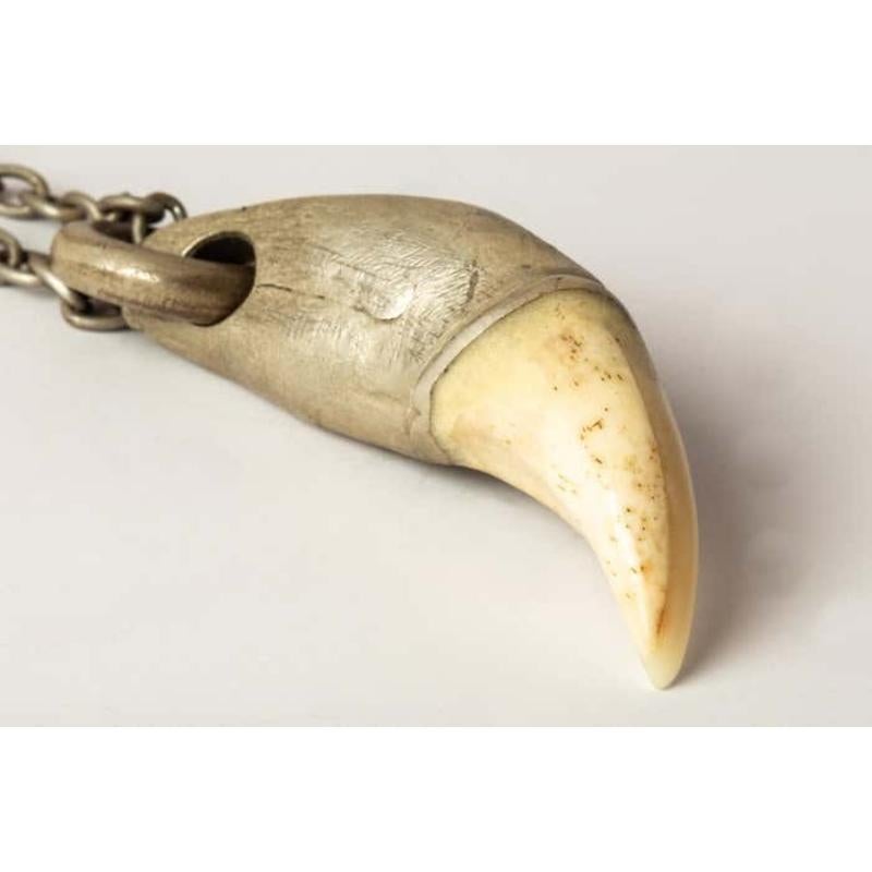 Pendant necklace in the shape of a bear tooth in acid treated sterling silver and bone, it comes on a 74cm chain. The bone form is completely hand carved. This item is made with deep respect to the magic of the particular animal it references and