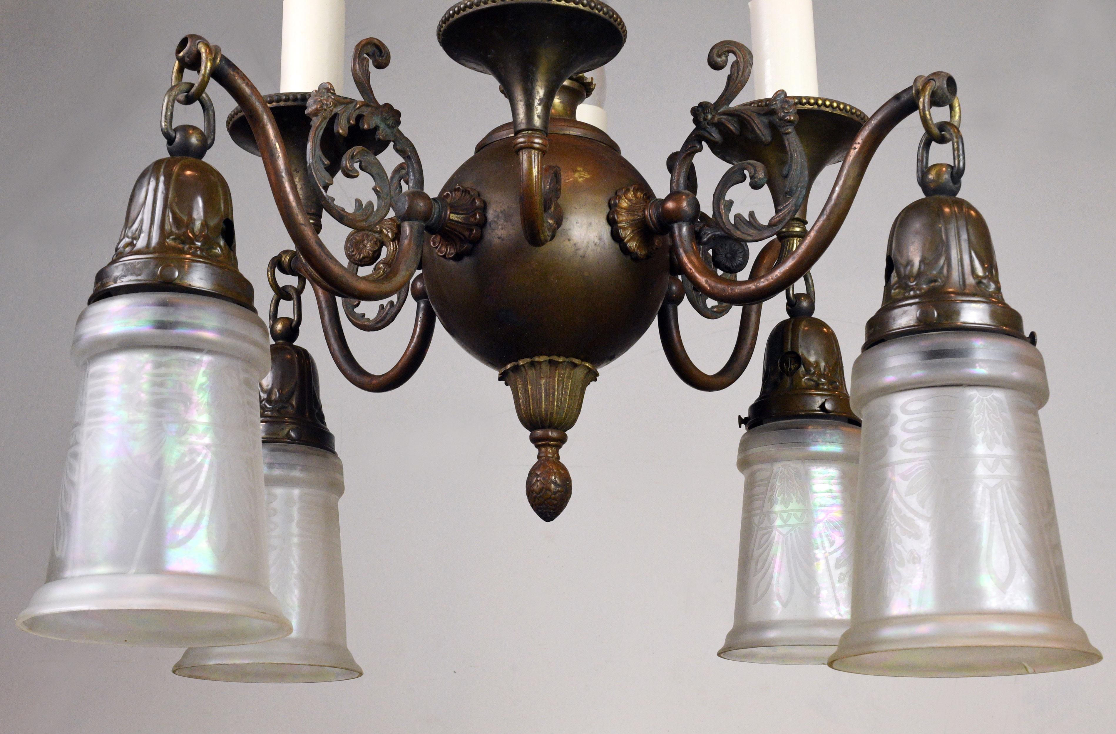 Exquisite brass Beardslee gas/electric chandelier with four candles and four iridescent glass shades. The combination both up and down lighting will provide ample illumination for any number of spaces. The fixture has a beautiful, rich patina: a