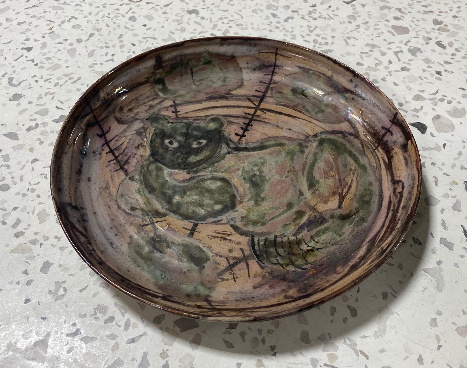 A relatively rare and wonderfully hand-painted charger featuring a mischievous cat by famed American/ California ceramist Beatrice Wood. The portrait of the feline features Wood's unmistakable whimsical and playful touch and is richly colored and