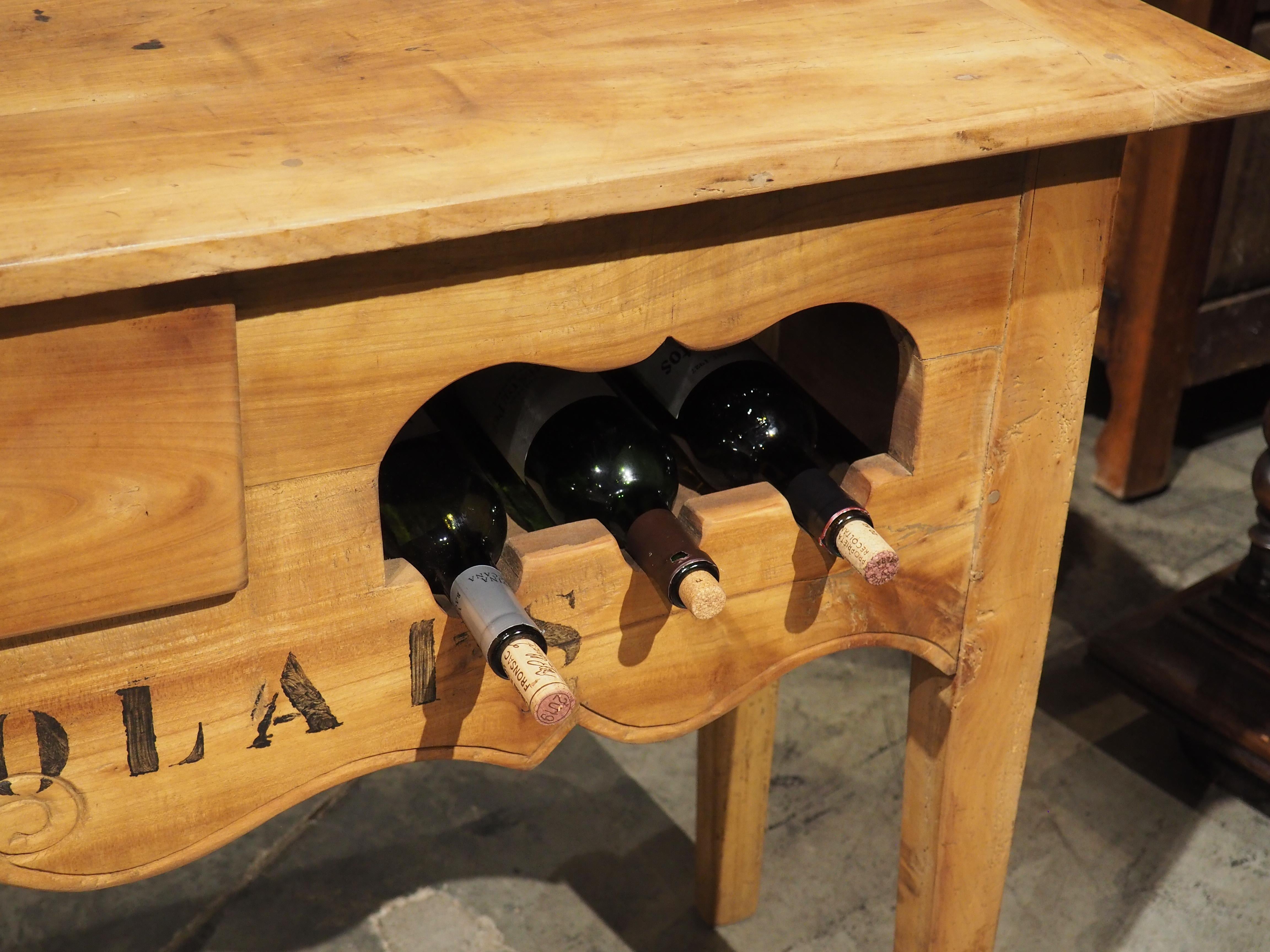 Infuse any wine room, bar area, or kitchen with a touch of aesthetics and functionality, thanks to this wooden French console table with six bottle wine rack. Two artfully designed three-bottle compartments on either side of a functional center