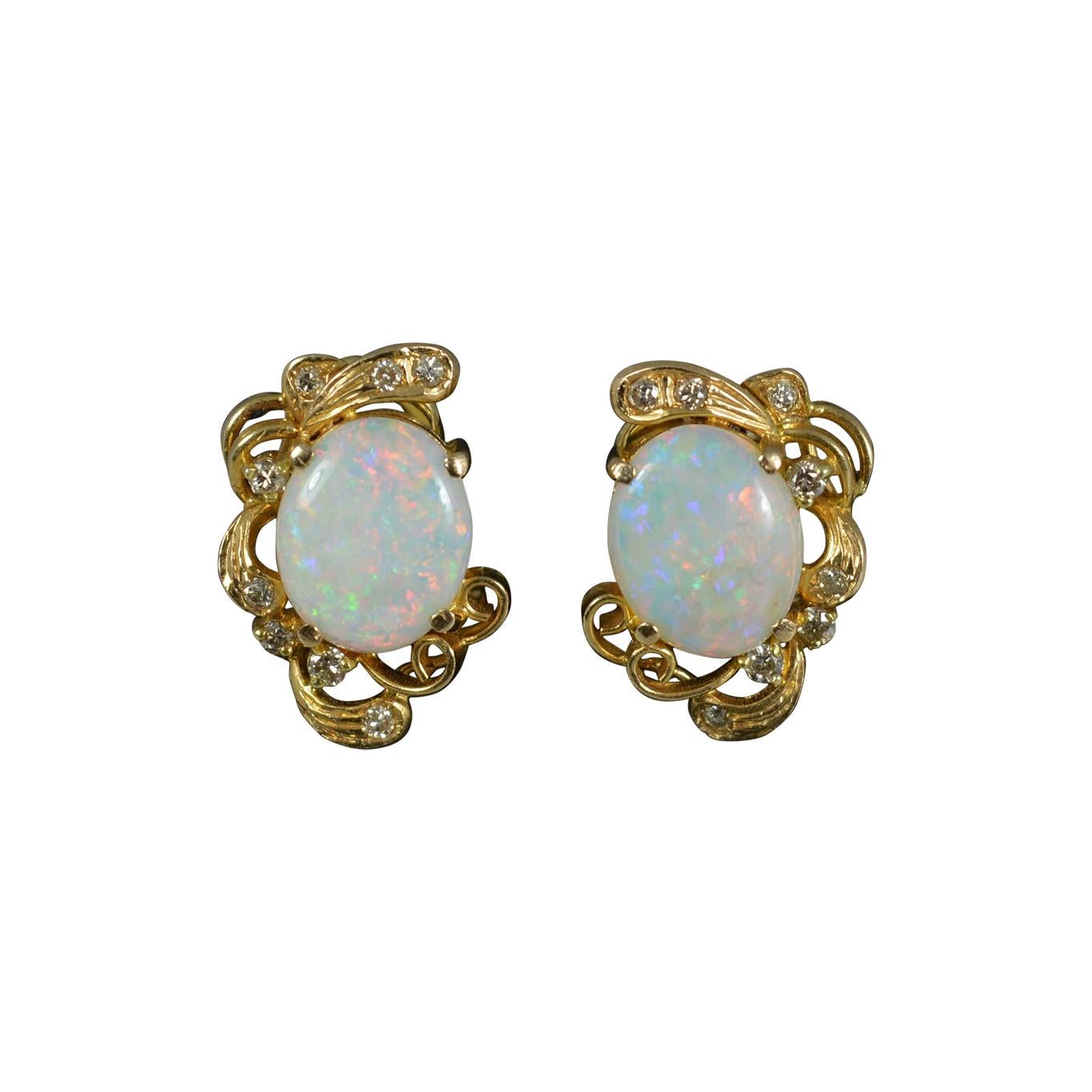 A stunning pair of 14ct Gold, Opal and Diamond cluster earrings.
Solid 14 carat yellow gold example.
Designed with a large oval shaped opal to each. Set in four claw setting. 8mm x 10mm.
Eight small diamonds in a scroll gold surround.
12mm x 18mm