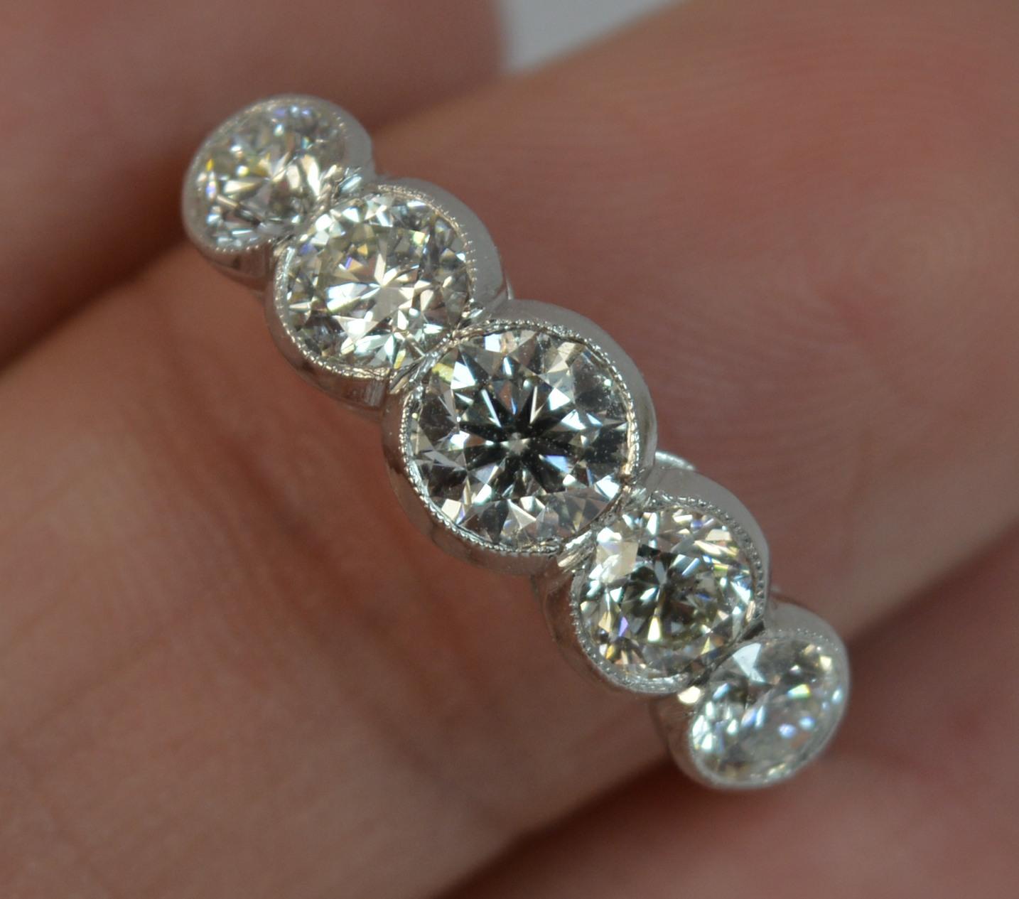 A Platinum and Diamond five stone design ring.
SIZE ; N UK, 6 3/4 US
​The natural round brilliant cut diamonds are each in bezel rubover settings. 

Graduated round brilliant cut natural diamonds to total approx 1.75 carats. Very bright, clean and