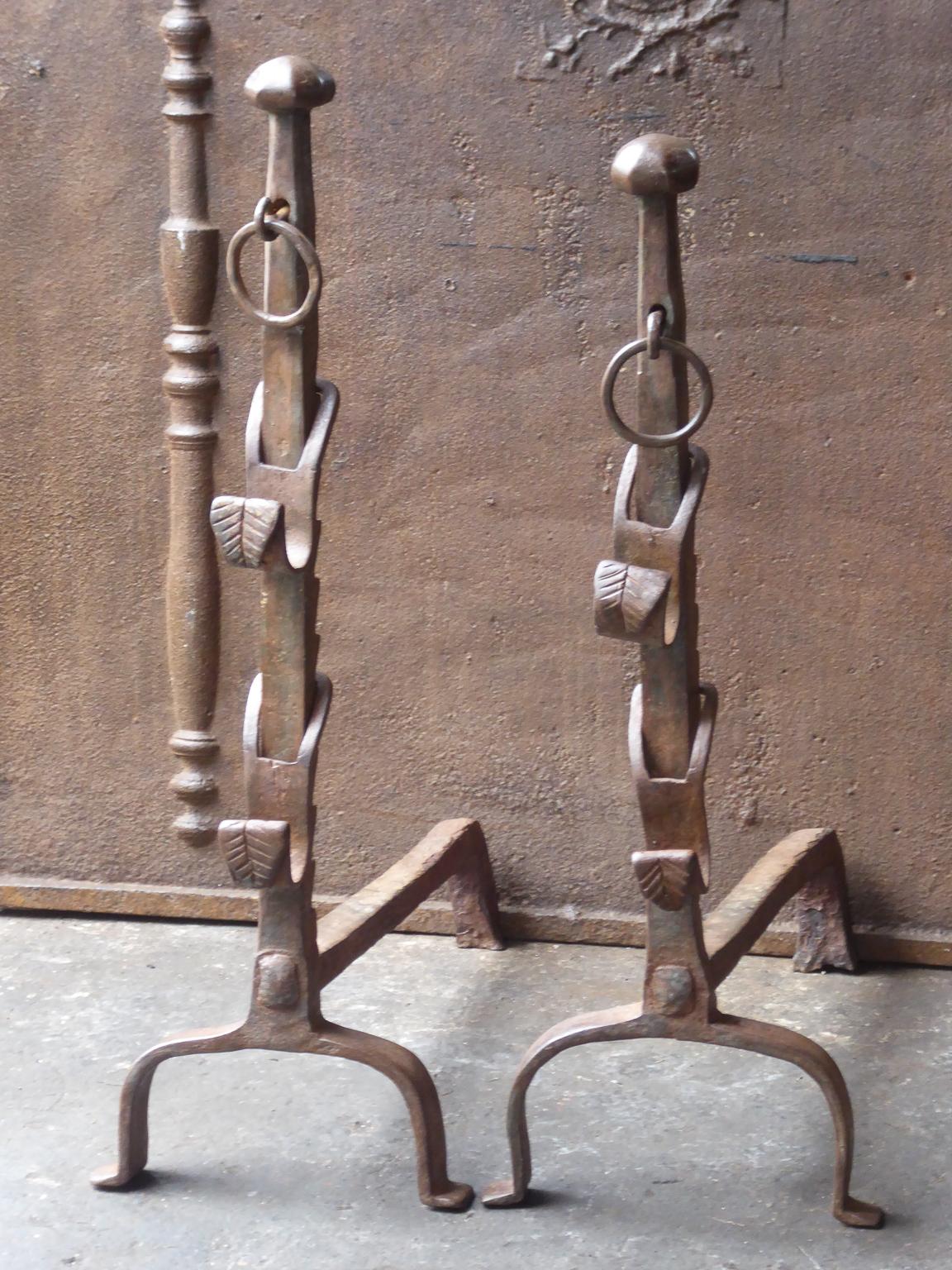 17th-18th century French andirons made of wrought iron. The style of the andirons is Gothic. The andirons have spit hooks to grill food. They have a natural brown patina. Upon request it can be made black. The andirons are beautifully carved.