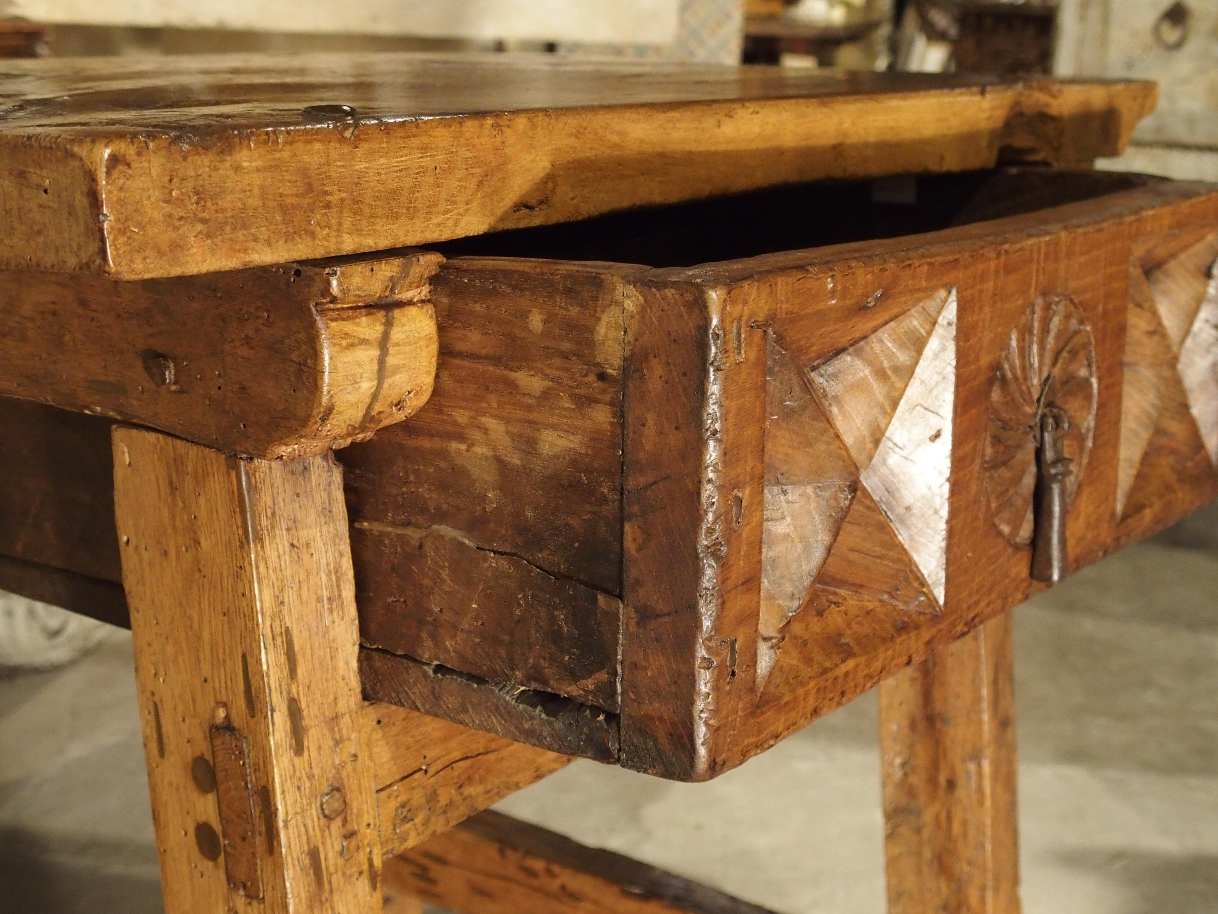 From Spain, this wonderful walnut wood side table dates to the 1600s. Its drawer frontage has deep geometric carving, with slanted rectangular legs and stretchers. The primary boards used for this table were all made from thick planks of walnut and