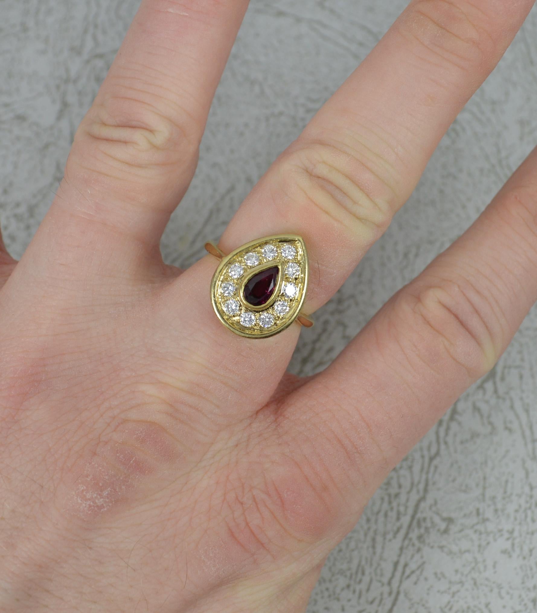 A striking cluster ring.
Solid 18 carat yellow gold shank.
Designed with a pear cut ruby to centre, full bezel setting. Surrounding are many round brilliant cut diamonds, 0.4 carats, vvs clarity f-g colour.
13mm x 17mm cluster head.

CONDITION ;
