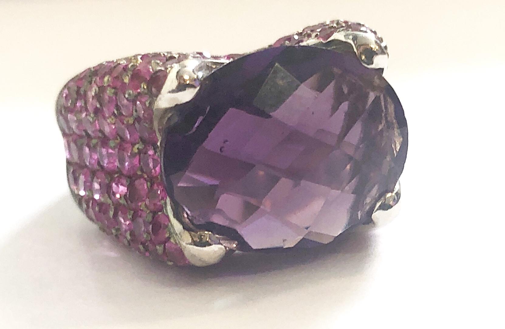 Beautiful 18KT White Gold Amethyst Ring 
Centered by an Amethyst, and surrounded by pink sapphires, weighing approximately 6 cts, measuring approx. 
14 mm x 12mm ,

weighing approximately 5.4 cts.
12.45 grams (gross), size 6 1/2
