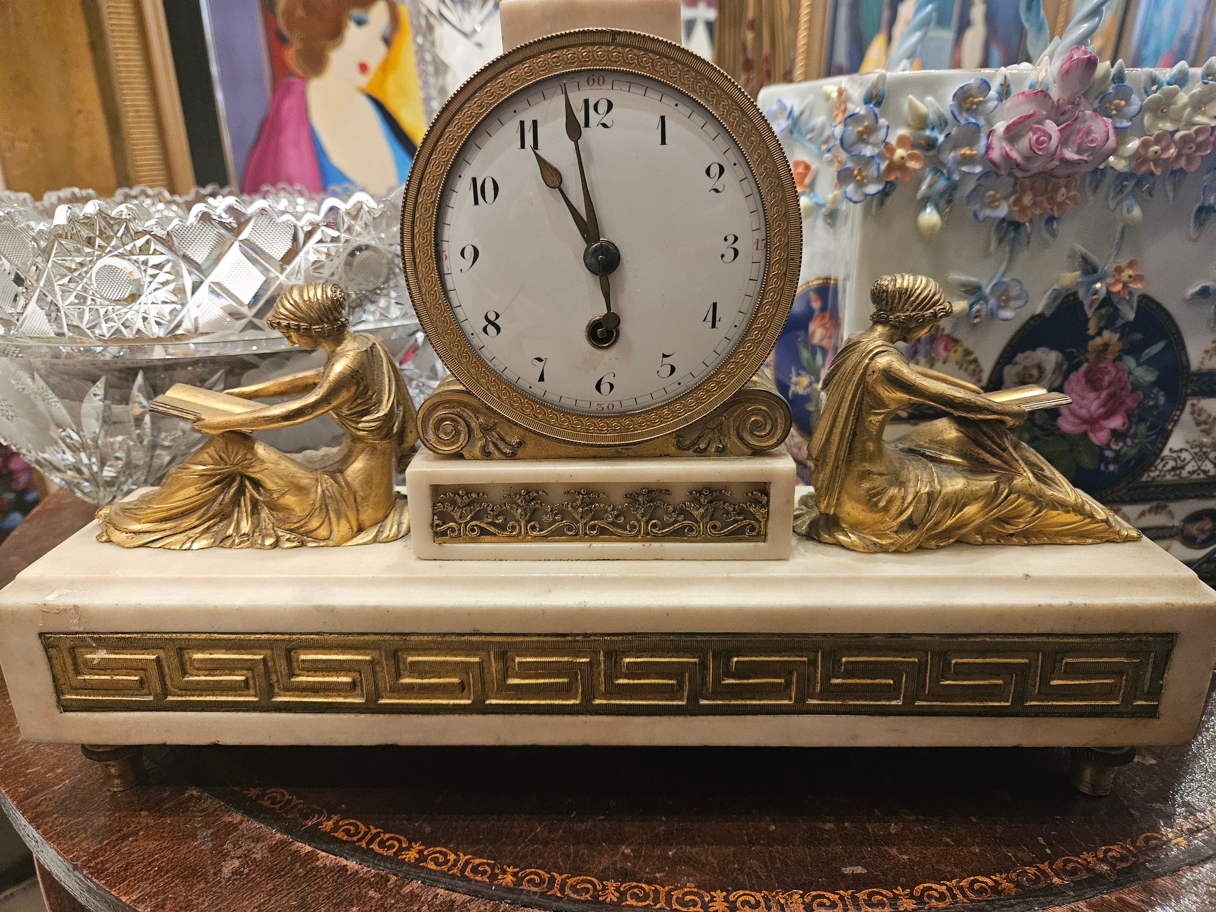 A Magnificent 18th Century English Gilt Bronze and White Marble Clock. Clock is Beautifully Comprised with a Bird Form Finial over the Circular dial with Arabic Numerals, flanked by Classical Maidens reading, the Base with inset Greek Key