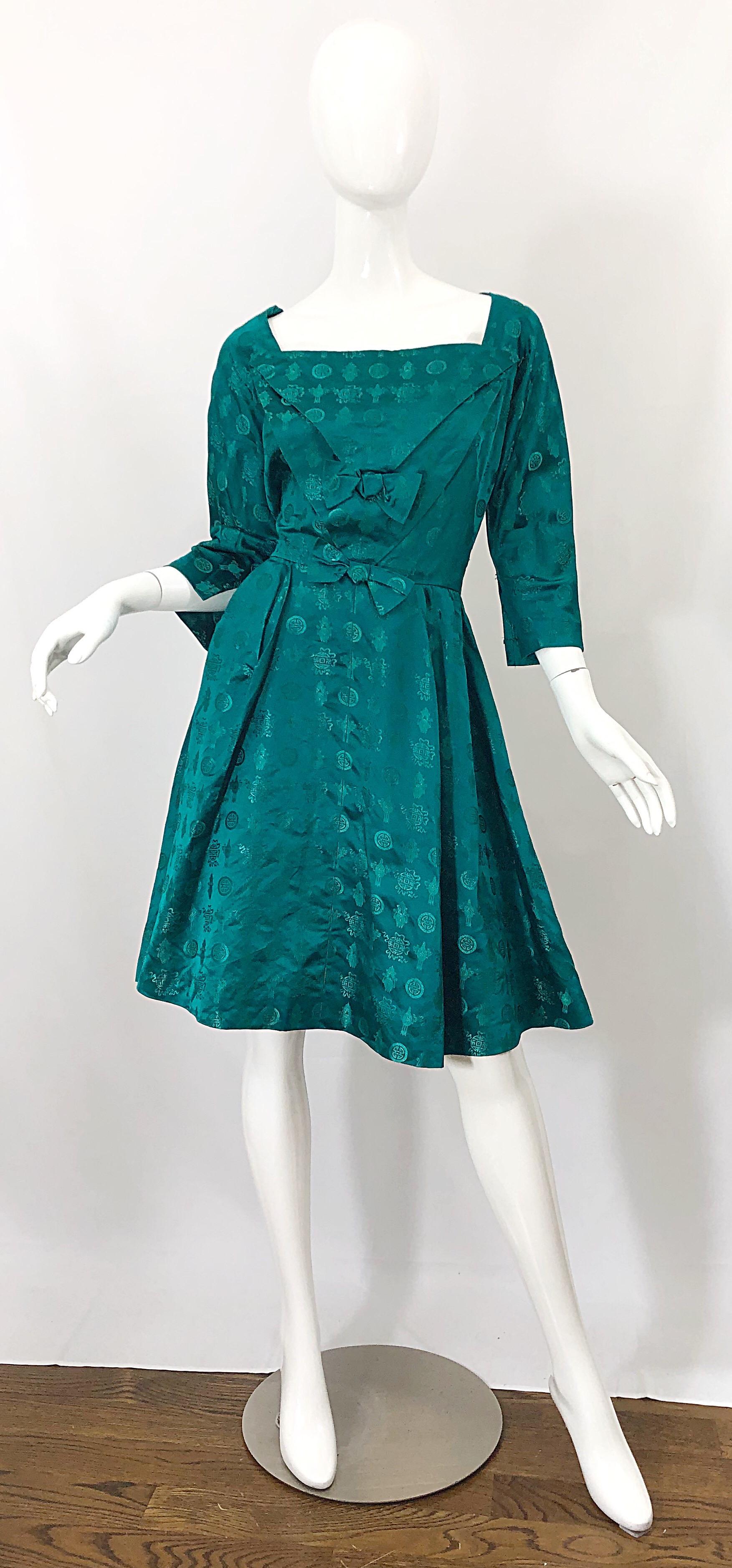 Beautiful vintage 50s emerald green Asian themed fit n' flare silk dress! Features a flattering square neckline with 3/4 length sleeves. Two bows at center waist. Full metal zipper up the side. Very well made, with heavy attention to details.