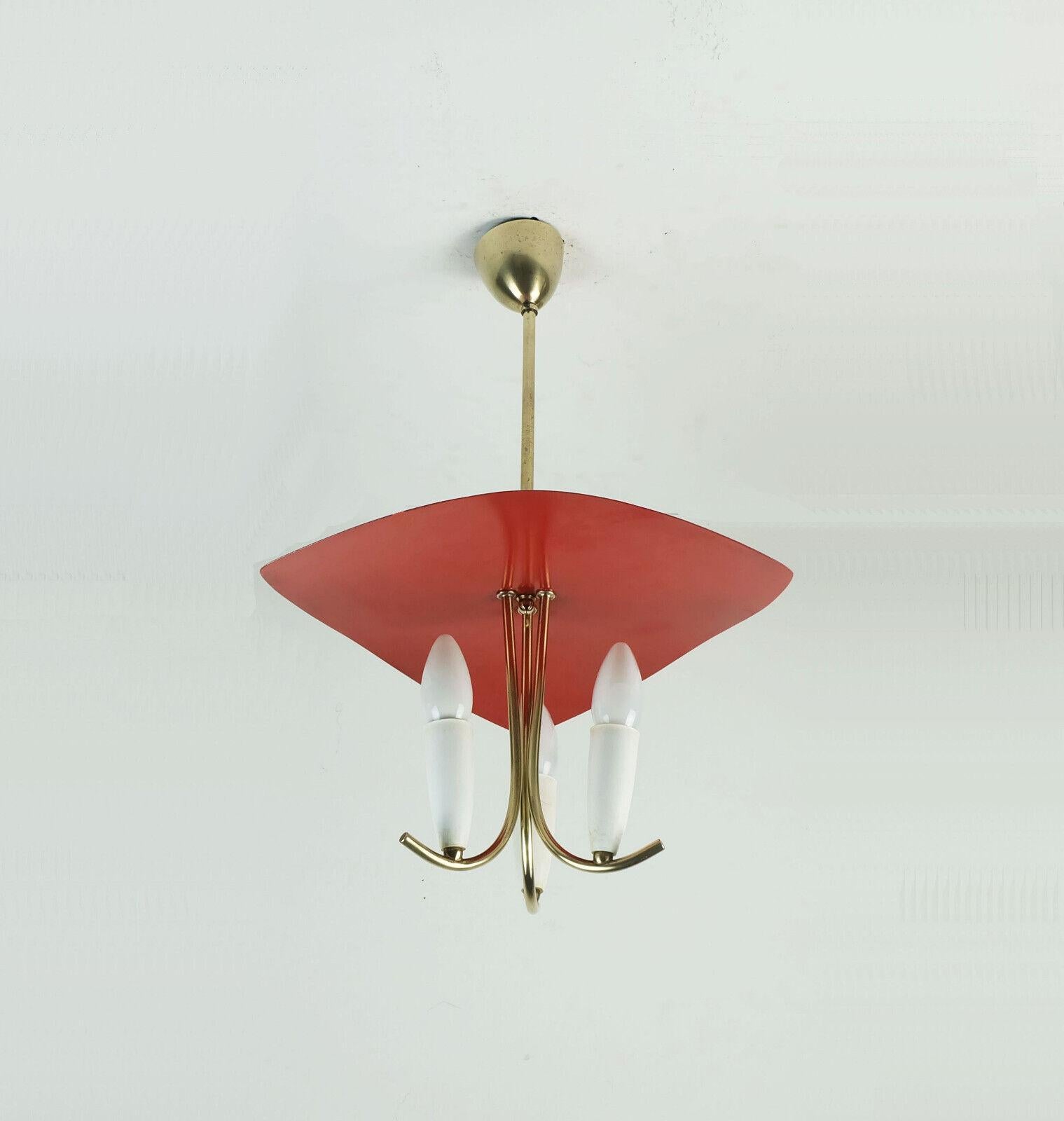 Very beautiful 1950s ceiling light. Curved brass frame with 3 arms. The sockets are covered by grommets made of white plastic. Above this is a triangular roof made of red lacquered metal. For light bulbs with E14 thread. 

Dimensions in cm:
Length
