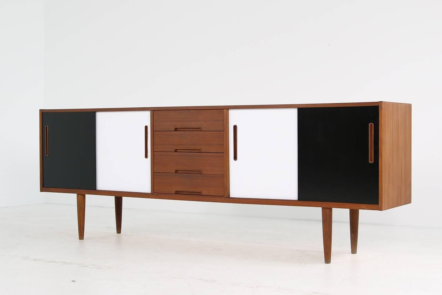 Beautiful 1960s sideboard by Nils Jonsson, made in Sweden by Troeds. Teak sideboard in very good condition, the top is very good, the painted sliding doors in black & white look great. Maple wood inside, four drawers. Rare piece in a fantastic look