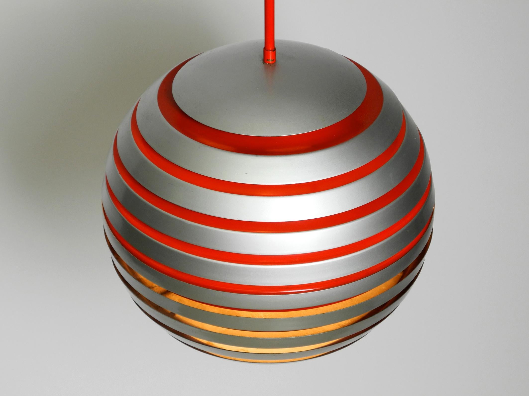 Beautiful original 1960s ball ceiling lamp with slats.
Great Space Age design from a Scandinavian production.
Heavy metal shade is assembled by individual rings.
The individual rings are partly painted red on the inside.
One E27 socket. The cord