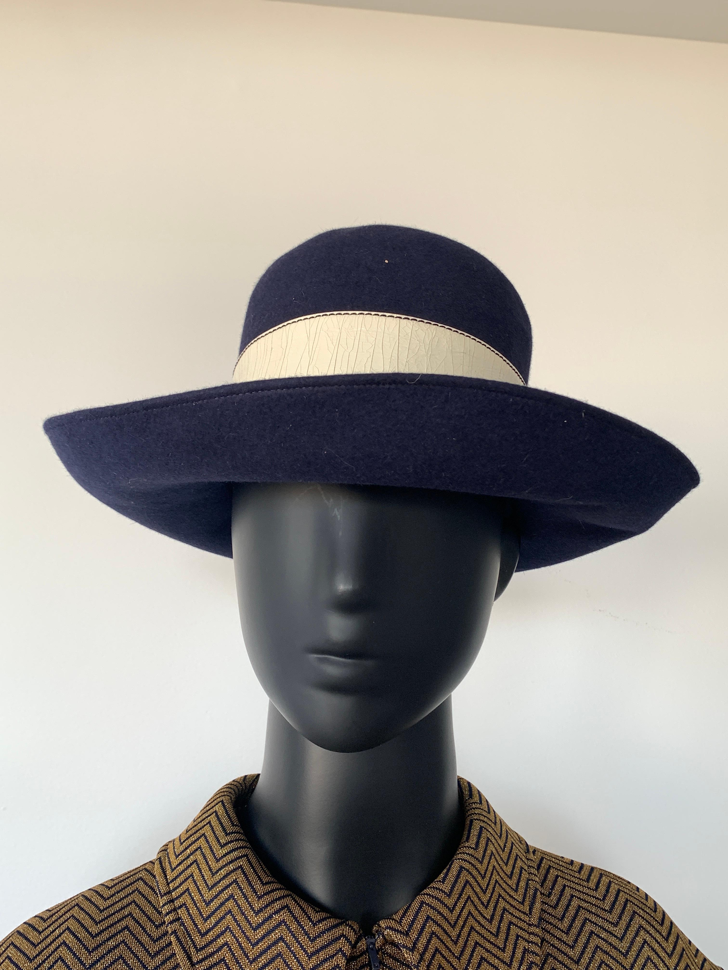 Beautiful 1970s Navy Felt Vintage Beautiful 1970s Vintage Hat. Blue felt with feature white vinyl ribbon and bow. 

Interior finished with petersham ribbon.

In great vintage condition.

Measurements are 
Circumference 54cm / 21inches
Crown height