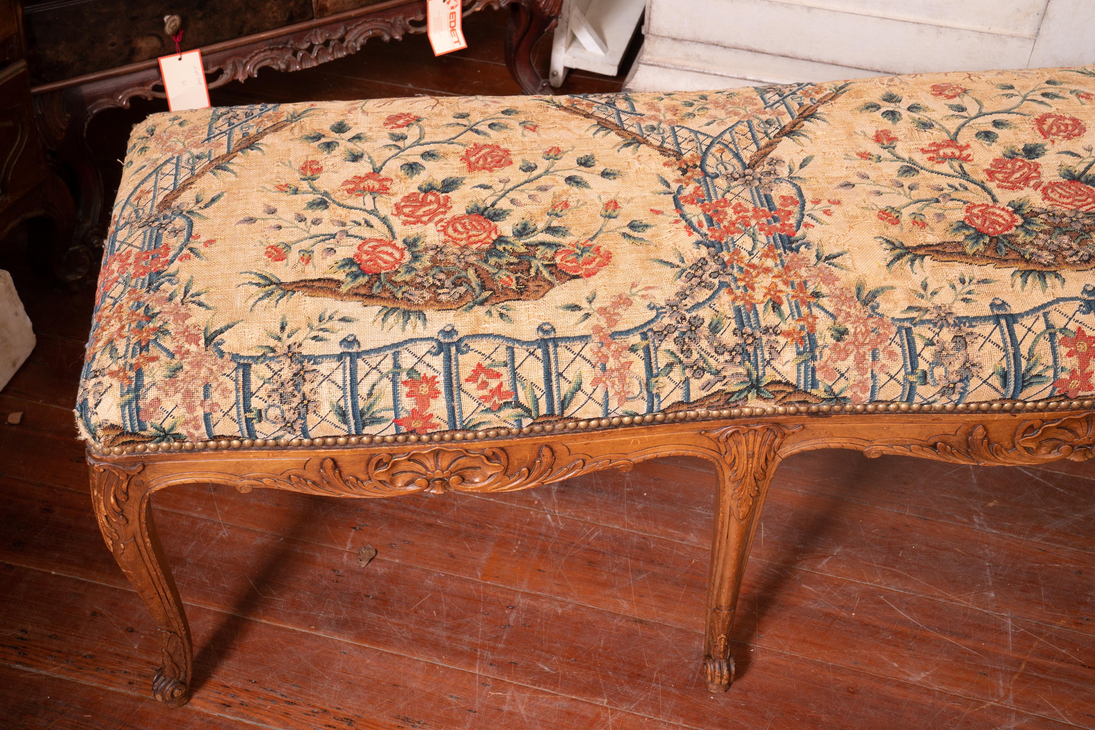 19th century. Carved honey colored walnut bench with original needlepoint cushioning.
