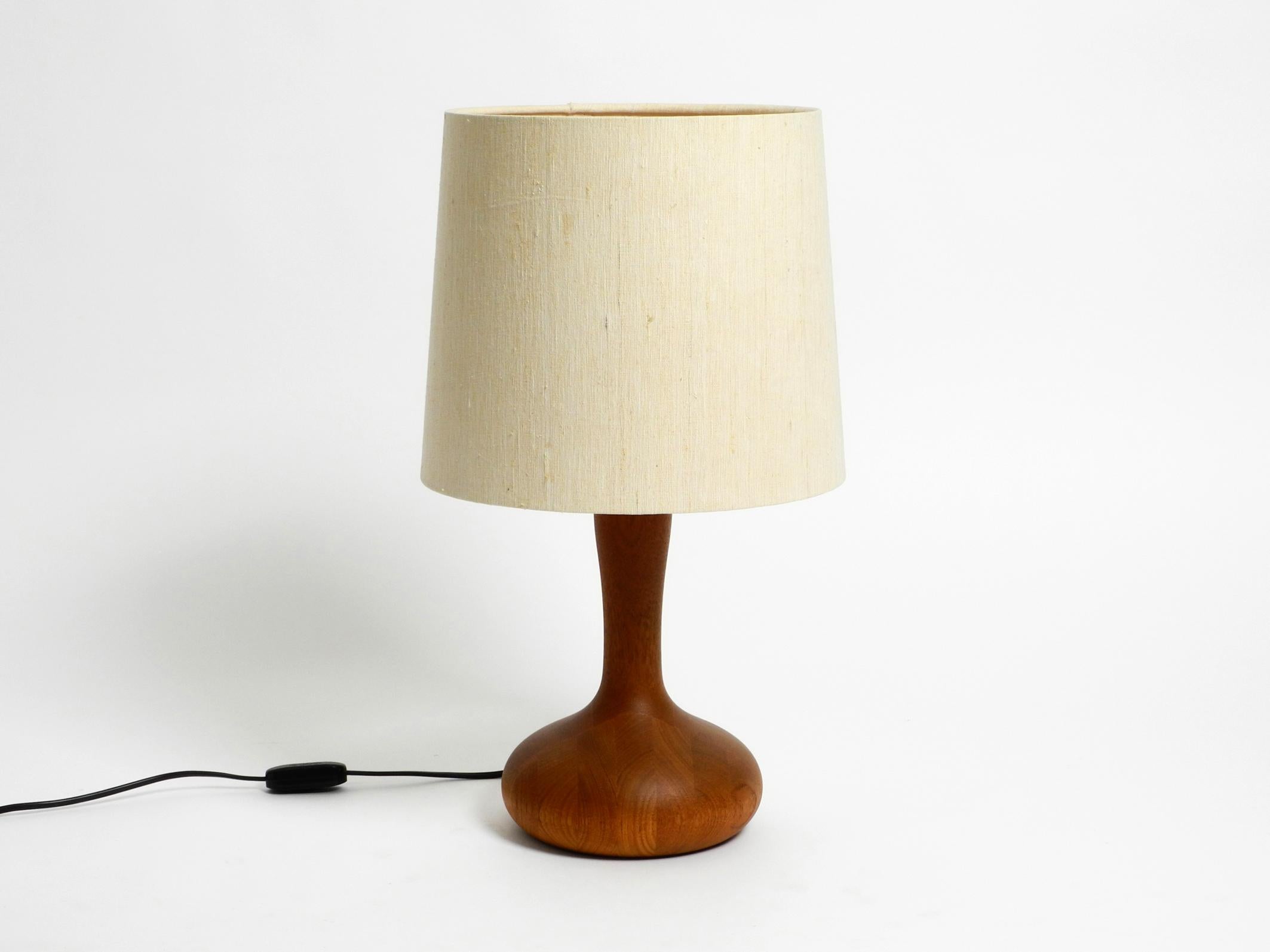 Beautiful minimalist 80s DOMUS teak table lamp with original wild silk fabric lampshade.
Foot is made entirely of teak. The large beige high-quality original fabric shade is covered with wild silk. Elegant design in very good vintage