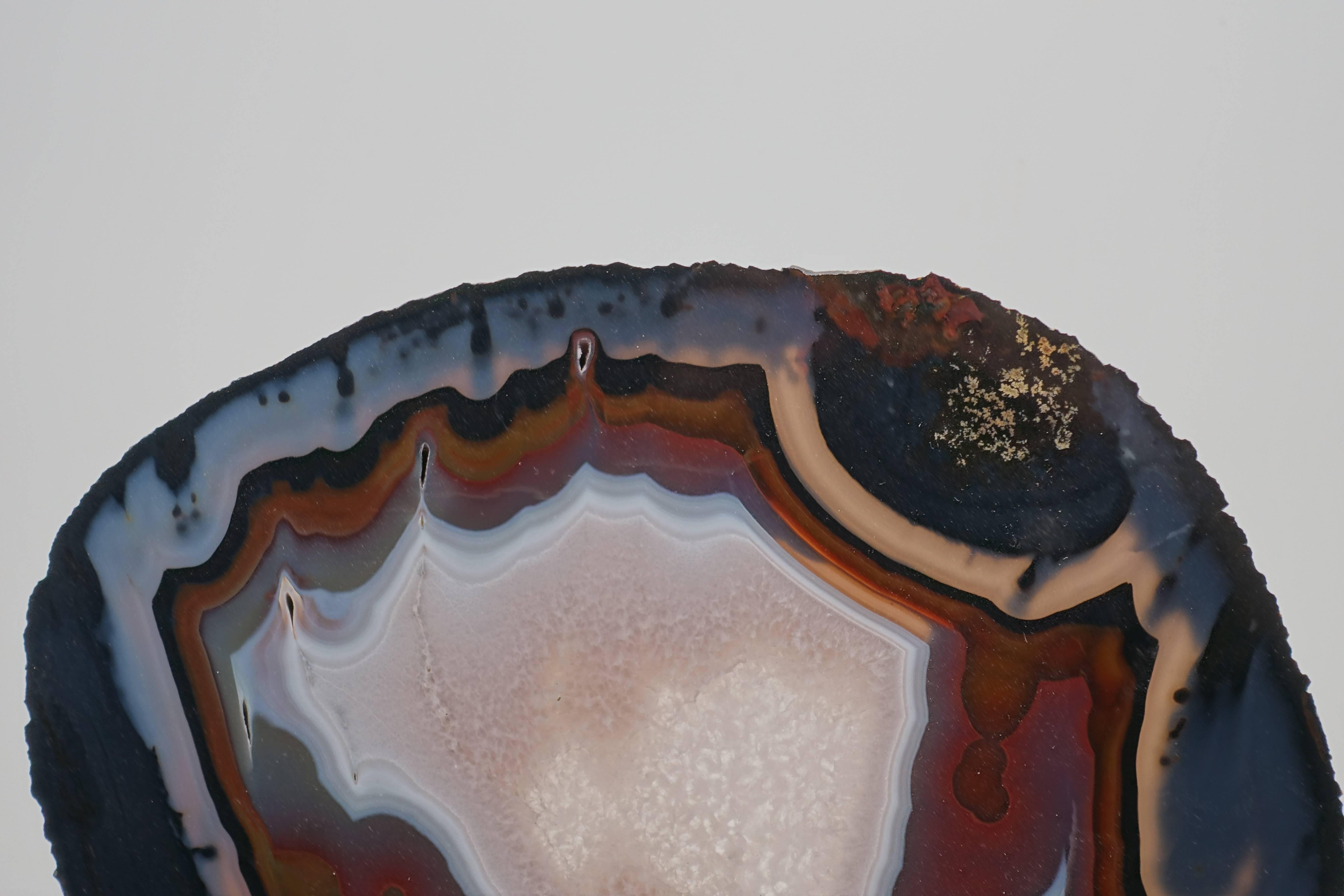 Shades of banded grey, rust, brown, black and crystalline white make this beautiful agate slice on a custom mount a stunning piece for your home or office.

Agate has long believed to promote protection, strength and harmony.