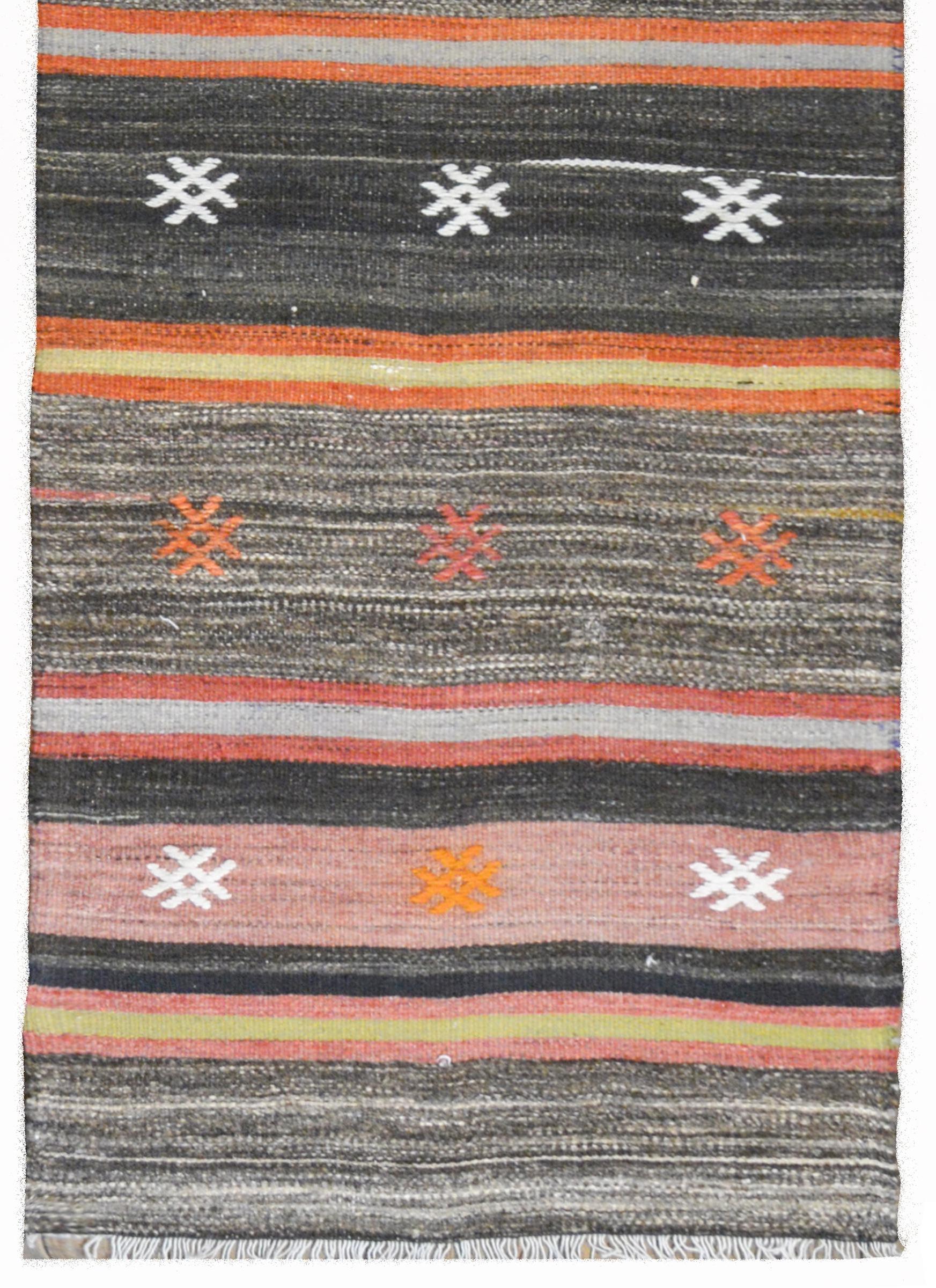 A beautiful vintage Anatolian Turkish Kilim runner with a crimson, gold, brown, and white, and crimson striped pattern with embroidered stylized flowers.