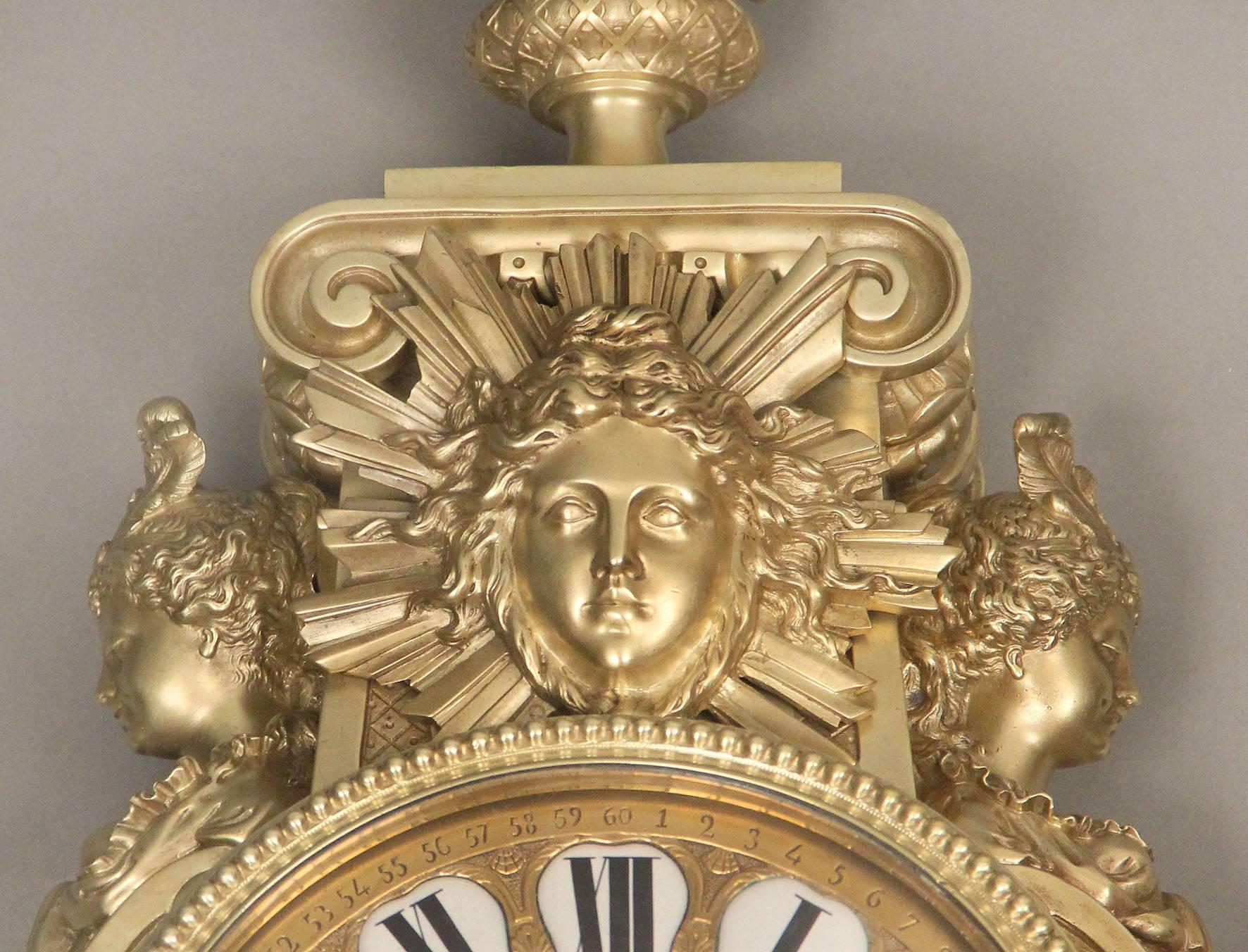 A beautiful and great quality late 19th century gilt bronze cartel clock

The large bronze clock topped by an urn above a large mask of Apollo with a sunburst, two scantily clad women busts on either side, centred with a finely detailed clock dial