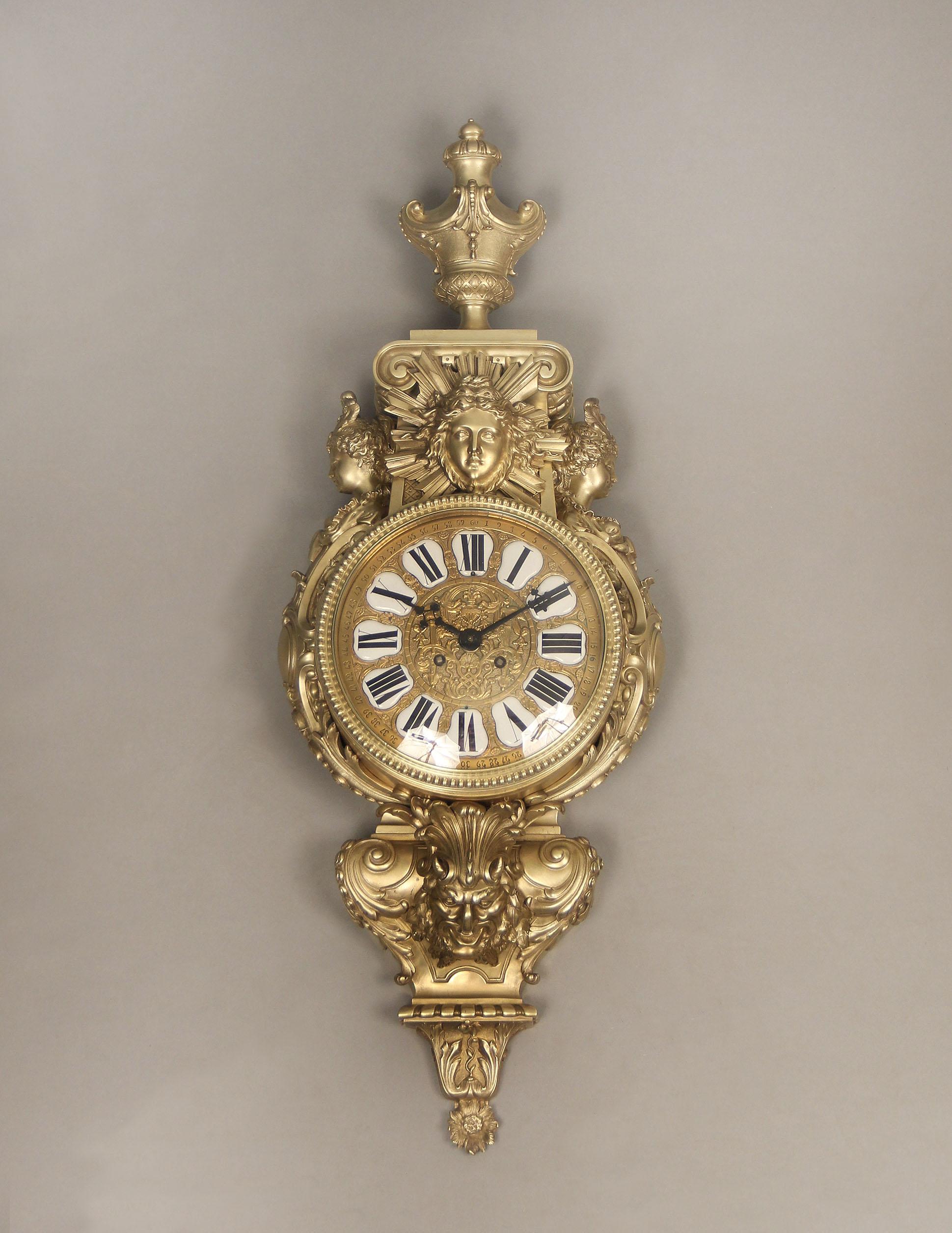 A Beautiful and Great Quality Late 19th Century Gilt Bronze Cartel Clock

The large bronze clock topped by an urn above a large mask of Apollo with a sunburst, two scantily clad women busts on either side, centered with a finely detailed clock dial