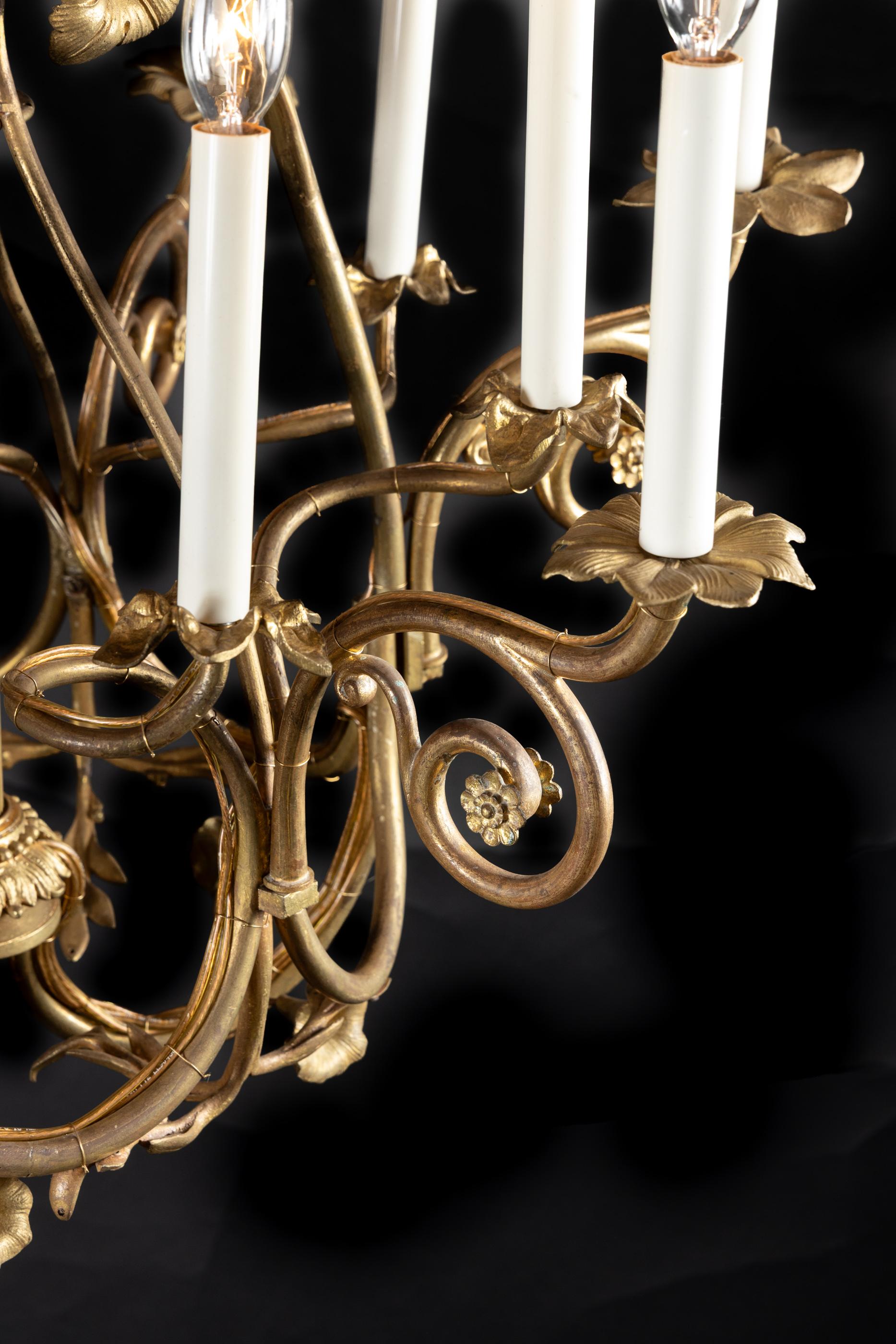 Questo lampadario unico in stile Art Nouveau francese è realizzato in bronzo e presenta un bellissimo stelo centrale scanalato. Il pezzo risale agli inizi del XX secolo ed è ornato da fiori in bronzo dall'alto verso il centro. Ogni luce è collegata