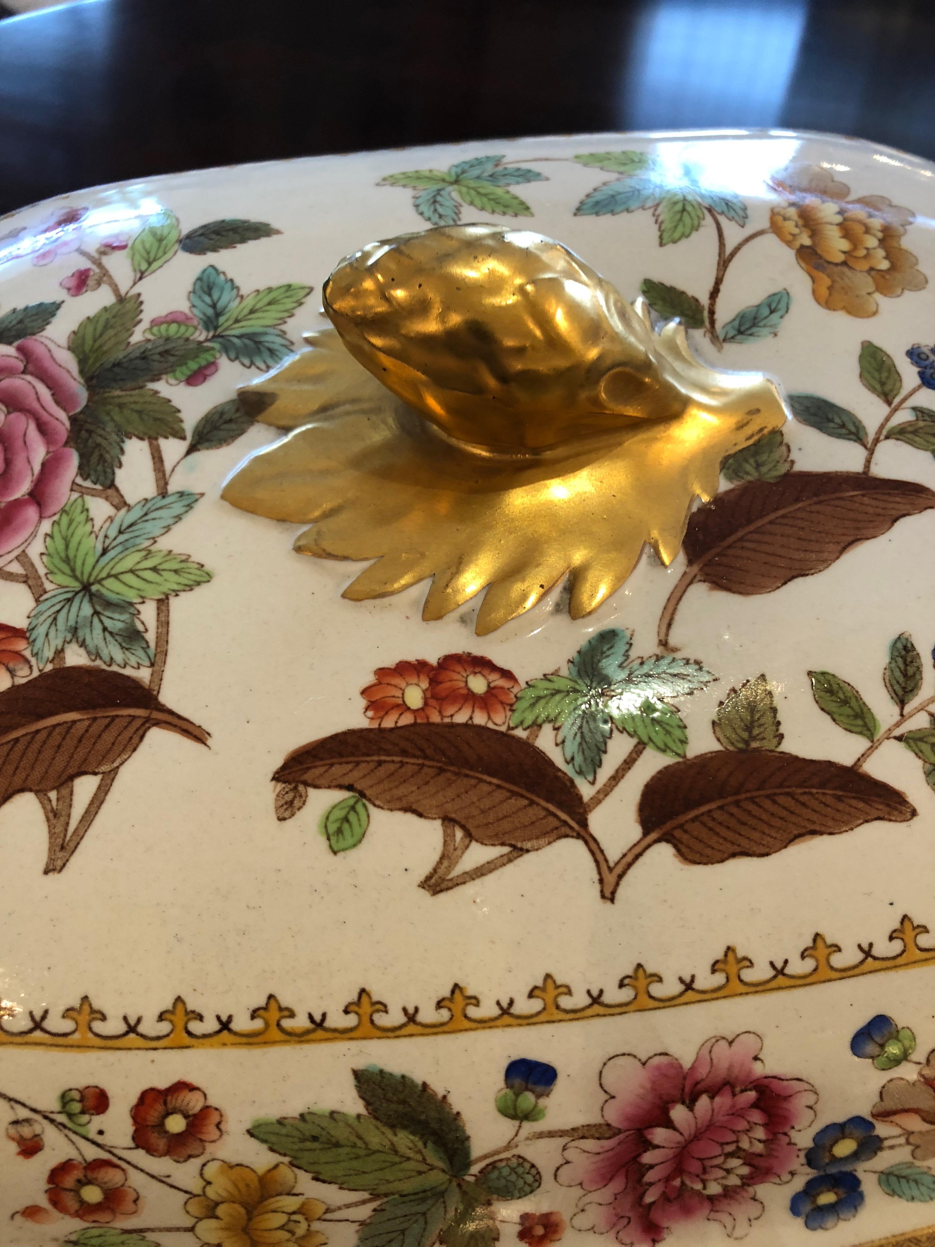 Gorgeous 19th century English porcelain soup tureen and underneath platter with floral and bird motif in gorgeous colors with gold leaf finial and handles, against a white background.
Measures: Tureen is 14 inches wide, 9.75 D, 8 H.

 