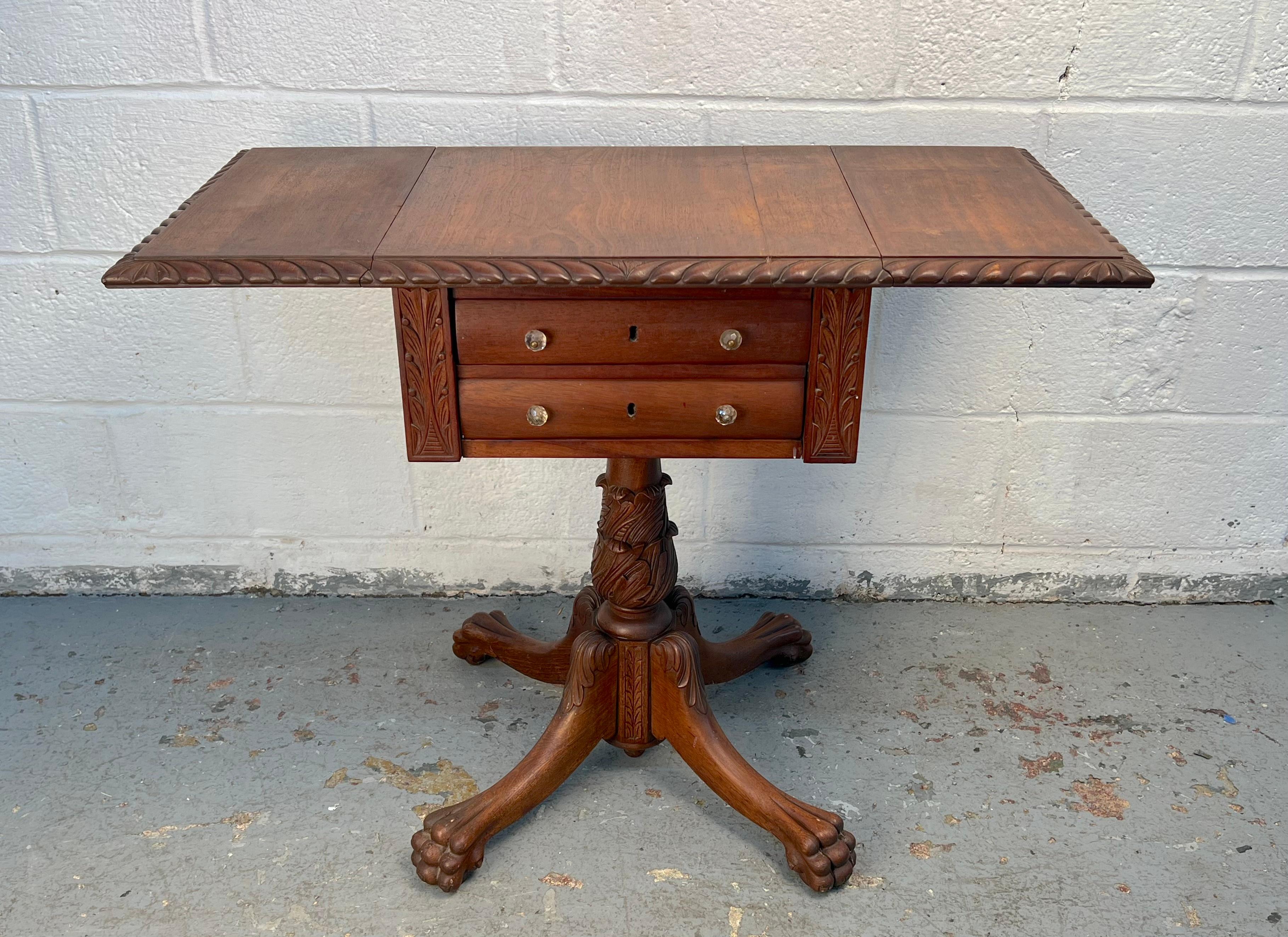 This distinguished American sewing table features a classic drop-leaf design, offering versatile surface space when needed. Crafted in rich mahogany with a warm patina, it showcases elegant  style details, including reeded legs and subtle carvings.