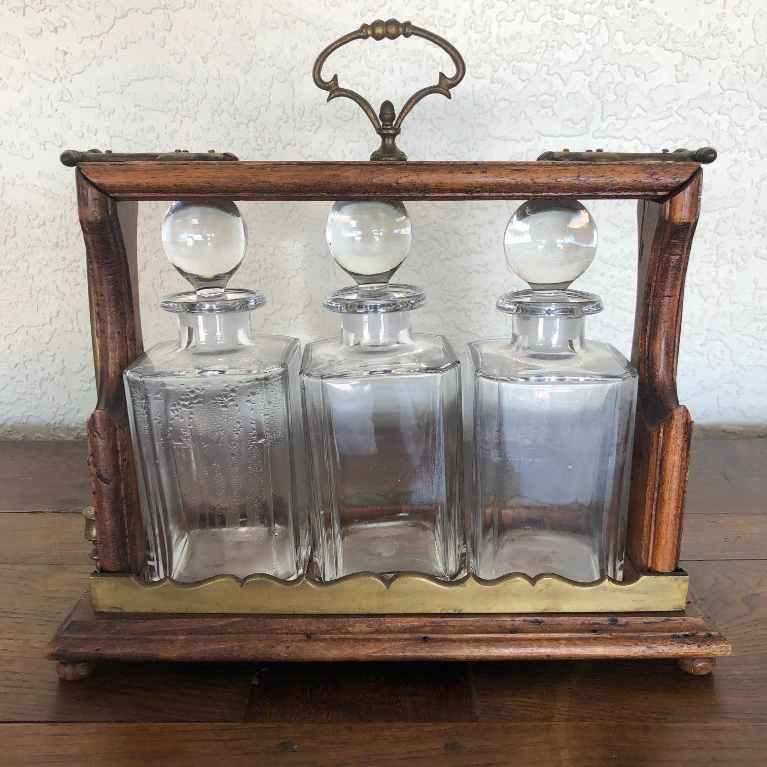 A very special three bottle crystal decanter tantalus executed with brass mounts on an oak platform. The latch mechanism functions as intended, and it has its original unusual cylinder brass lock and key. Another unusual feature of this tantalus is