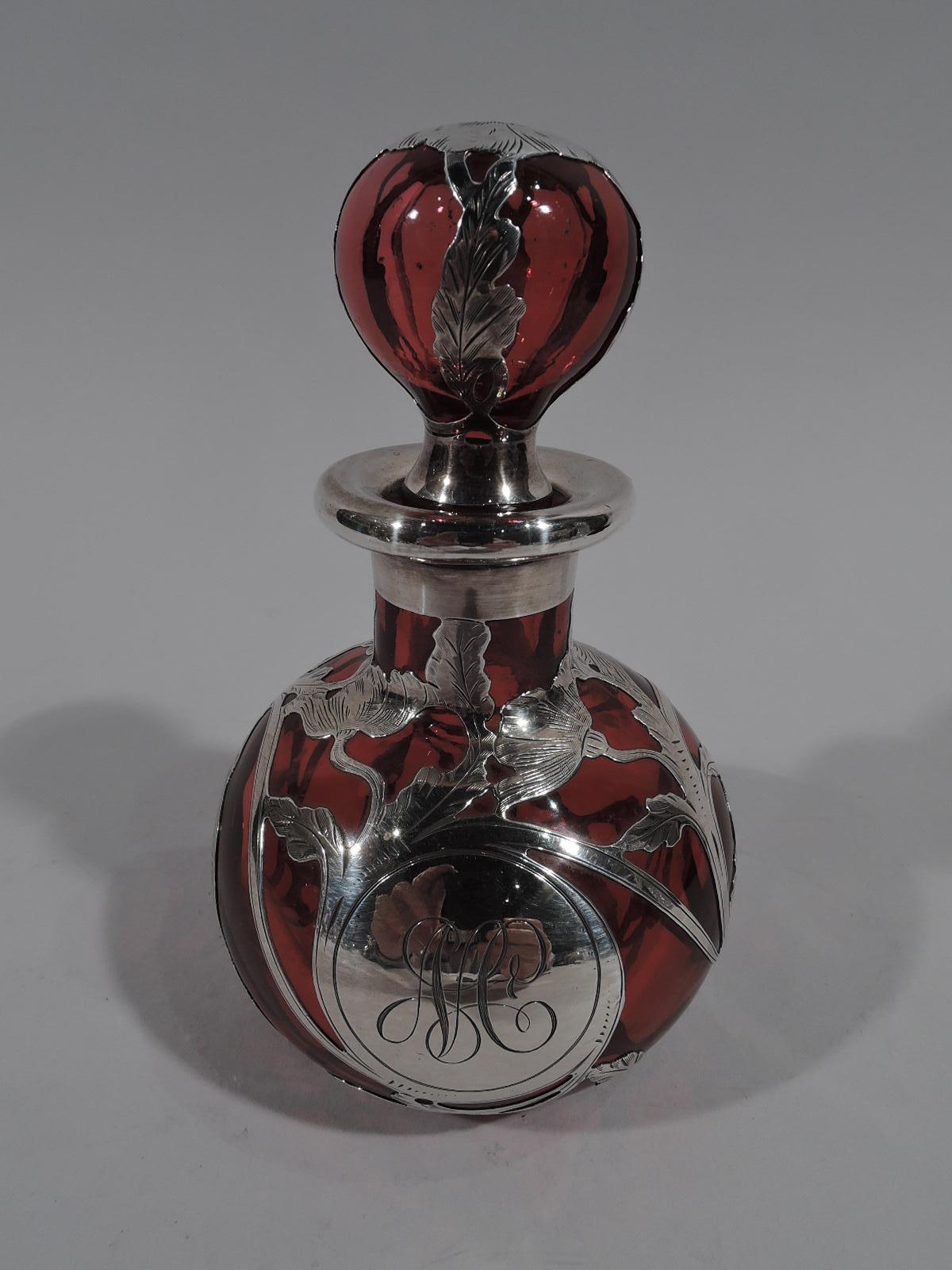 Beautiful turn-of-the-century red glass perfume with silver overlay. Made by Gorham in Providence. Globular bottle with short neck and ball stopper. Classical rinceaux overlay and circular frame engraved with interlaced monogram. Maker’s stamp and