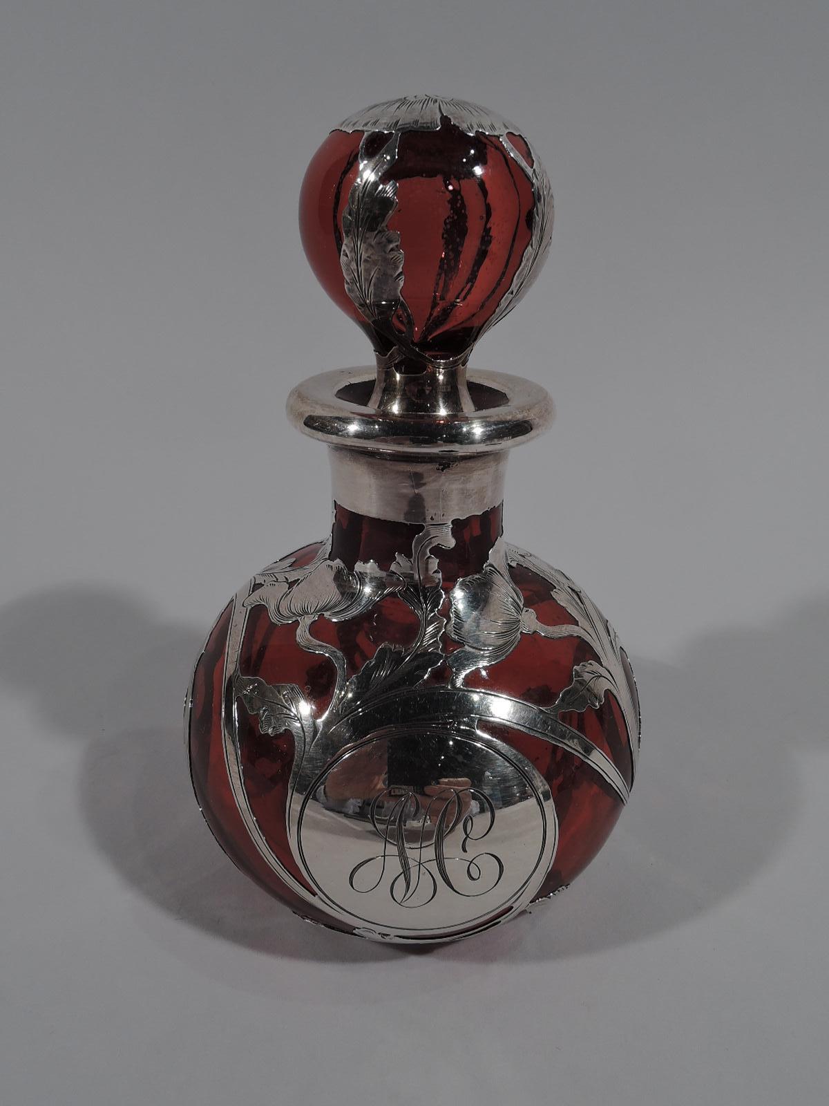Beautiful turn-of-the-century red glass perfume with engraved silver overlay. Made by Gorham in Providence. Globular bottle with short neck and ball stopper. Classical rinceaux overlay and circular frame engraved with interlaced monogram. Maker’s