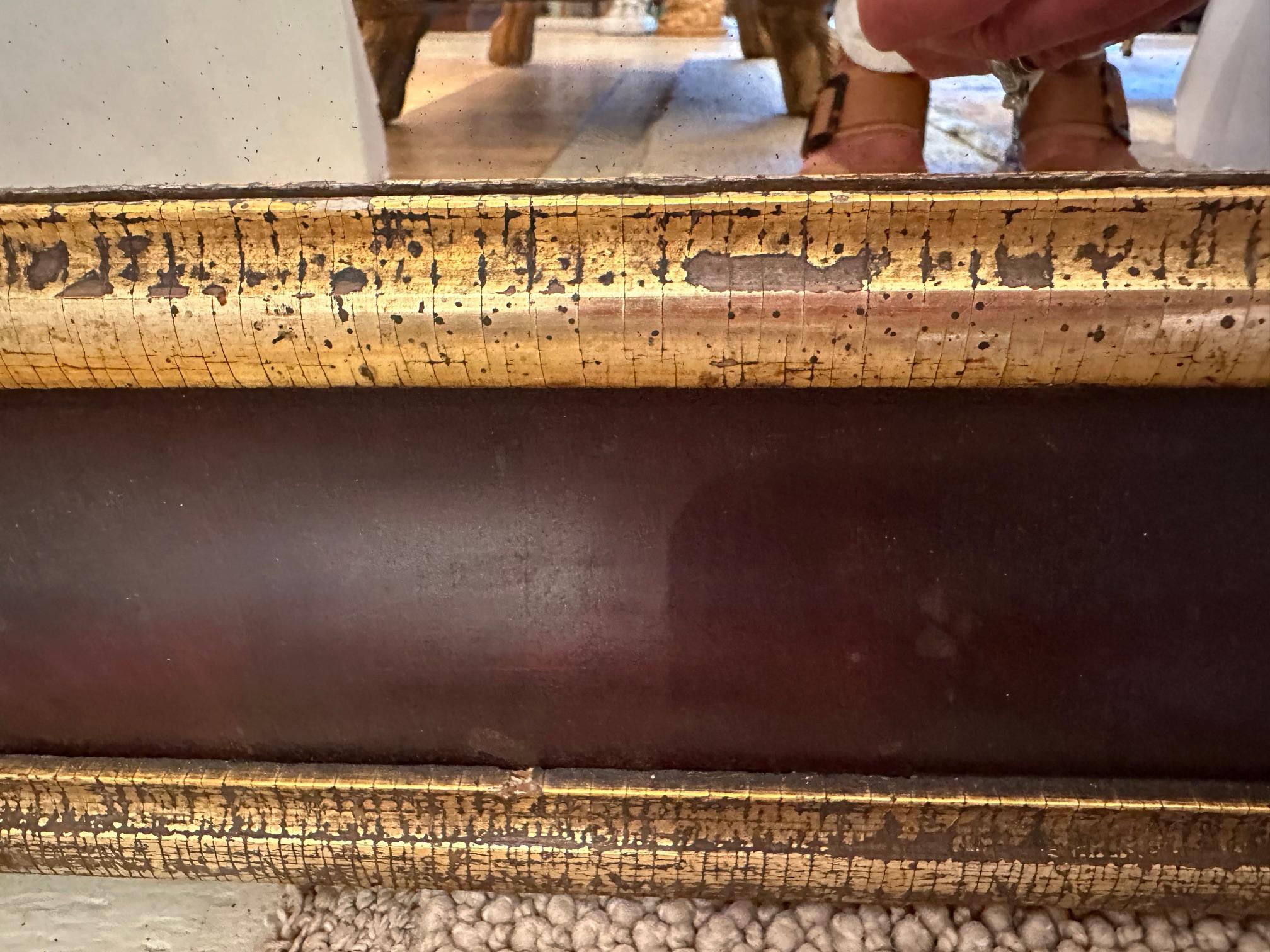 Antique mahogany mirror having rich gilded speckled filet and border on the frame.  Great aged look.
Mirror 15.75” W x 36” H
Small clamshell chip under wood strip on mirror
Some aged spots on mirror