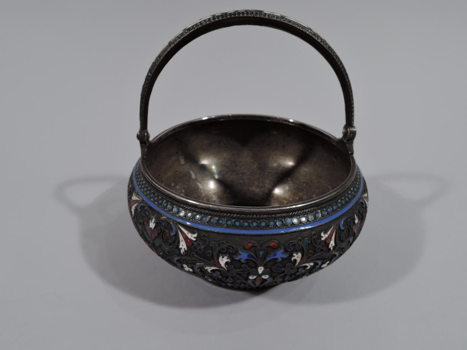 Beautiful Russian 875 silver basket with enamel, 1894. Curved sides flowing into short and inset foot. Tapering C-scroll swing handle. Sides stippled with scrolls and flowers between guilloche borders. Bold colors with “jeweled” highlights.