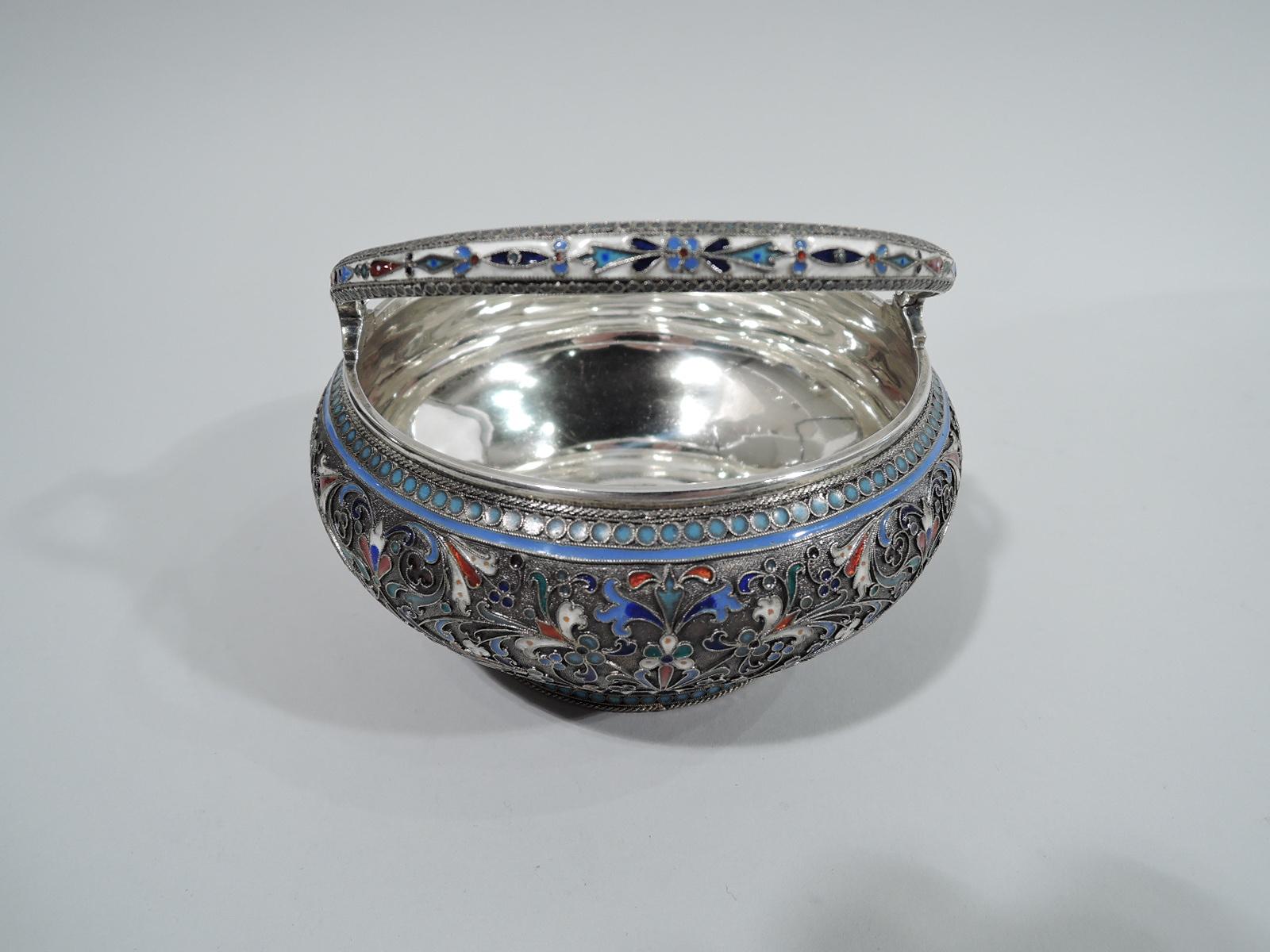 Beautiful Russian 875 silver basket with enamel, 1894. Curved sides flowing into short and inset foot. Tapering c-scroll swing handle. Sides stippled with scrolls and flowers between guilloche borders. Bold colors with “jeweled” highlights.