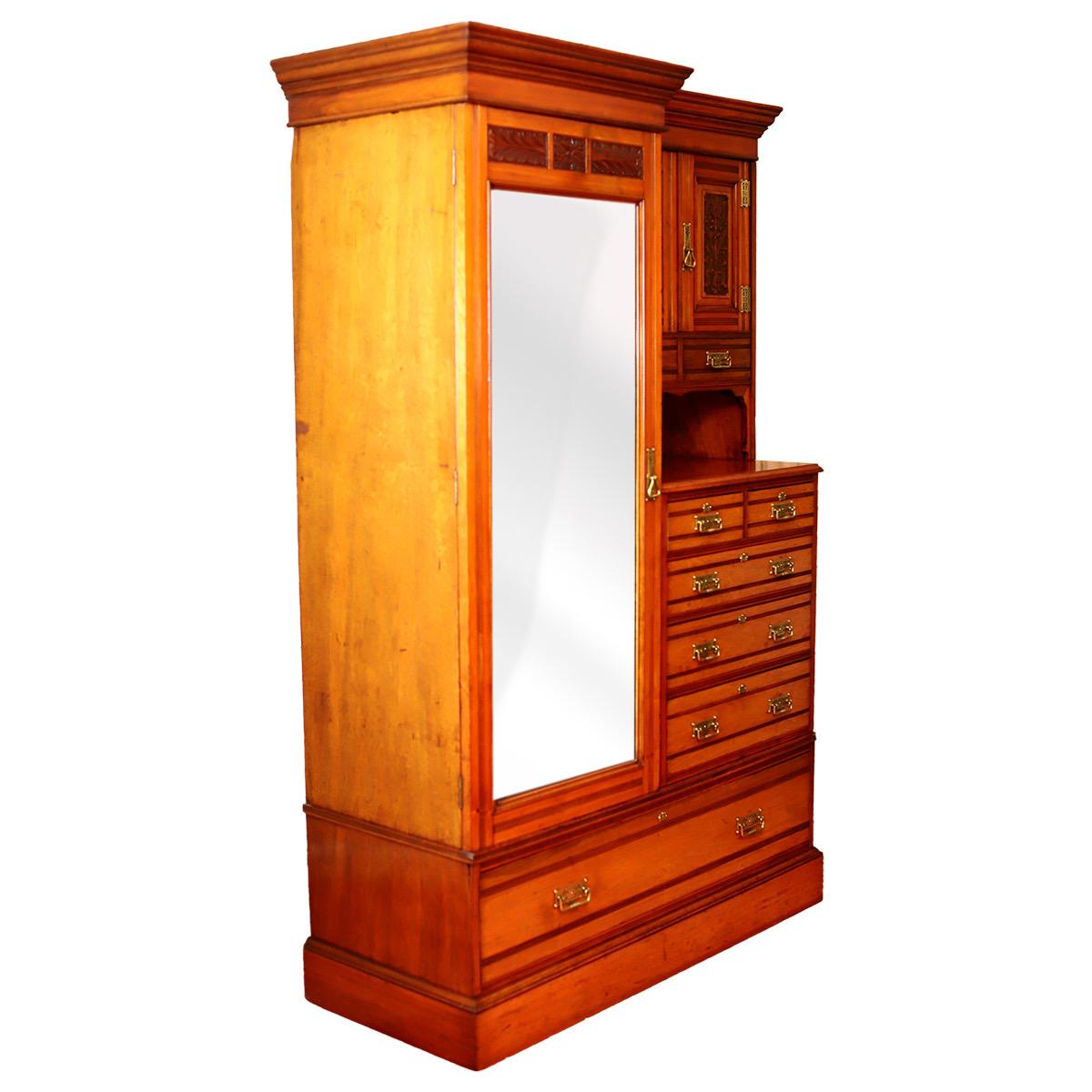 An late Victorian carved walnut combination wardrobe with shaped and moulded cornice, fitted a cupboard enclosed by bevelled plate mirror panelled door flanked by a cupboard enclosed by panelled door above 2 drawers, a recess and 3 further drawers,
