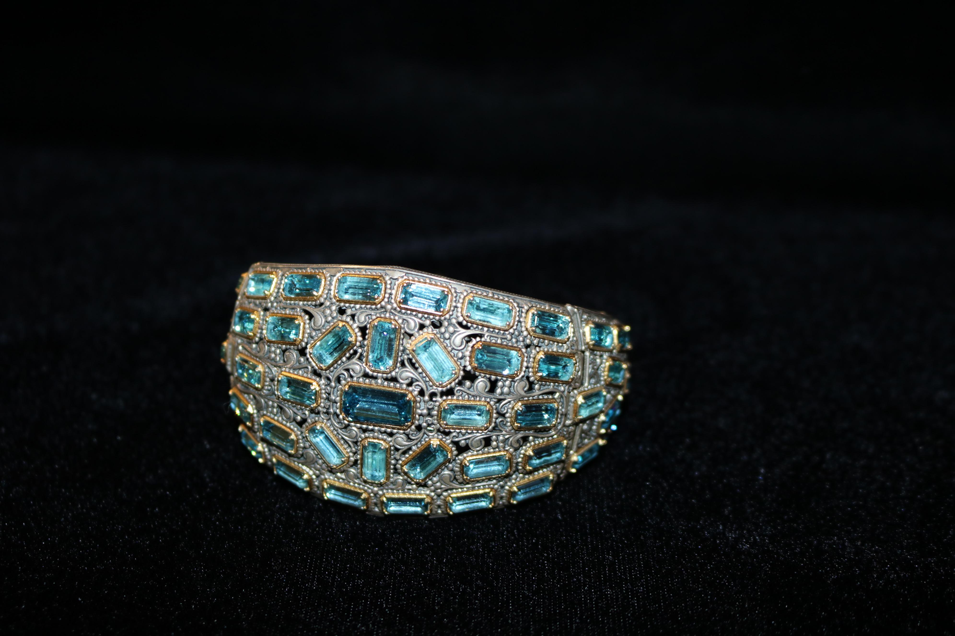 Pièce intemporelle de l'époque Art of Vintage, ce bracelet vintage exquis respire l'élégance et la sophistication.
Fabriquée en argent 925 et en or 18 carats, cette pièce comporte plus de 40 topazes bleues naturelles taillées en émeraude.  ce qui en