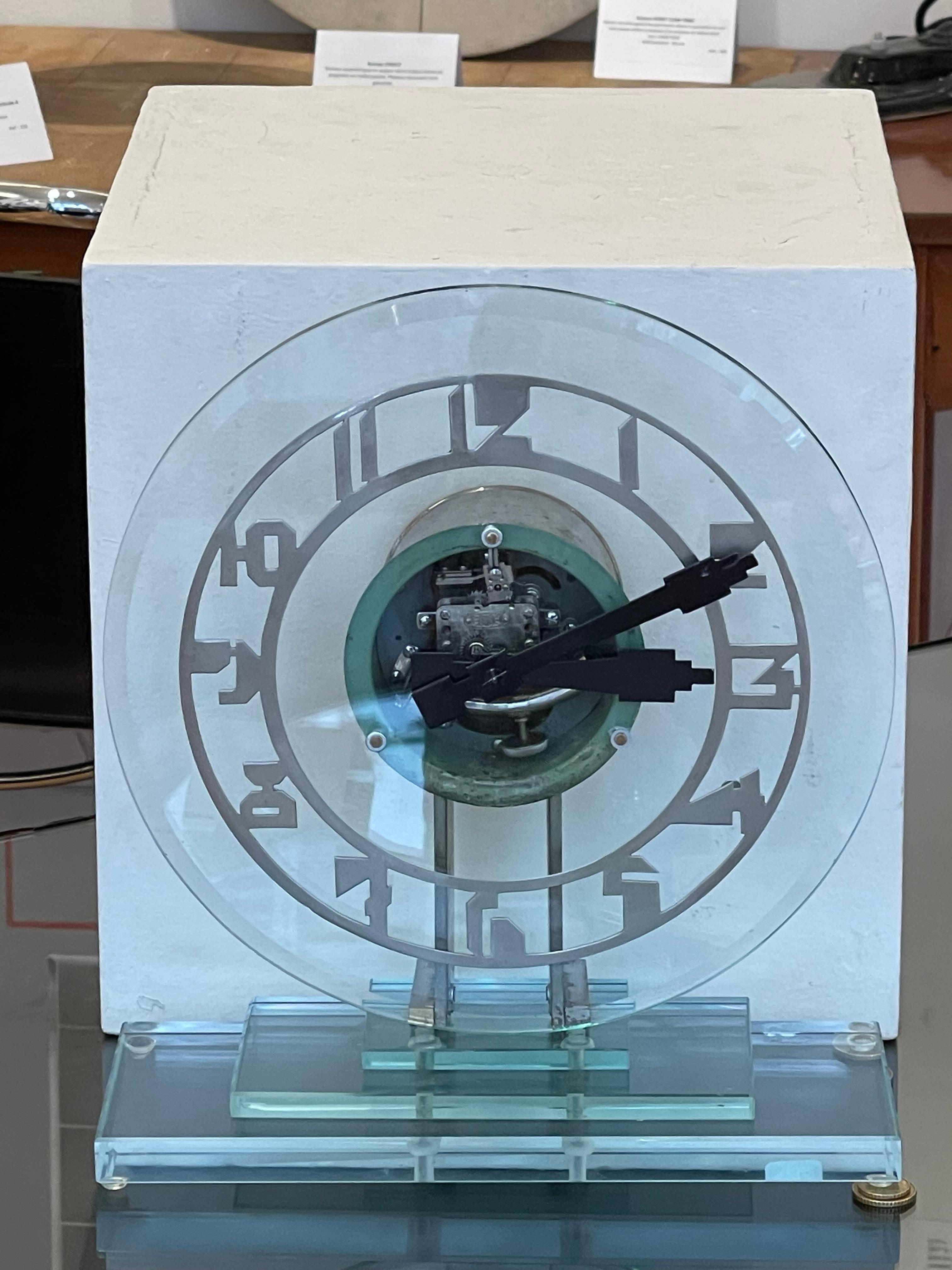 Exceptionnel pendule électrique (alimenté par une pile ronde standard LR14) Art déco en verre transparent avec boîtier rond nickelé sur un socle également en verre à trois étages. 

Le cadran, typiquement Art déco, est transparent et laisse