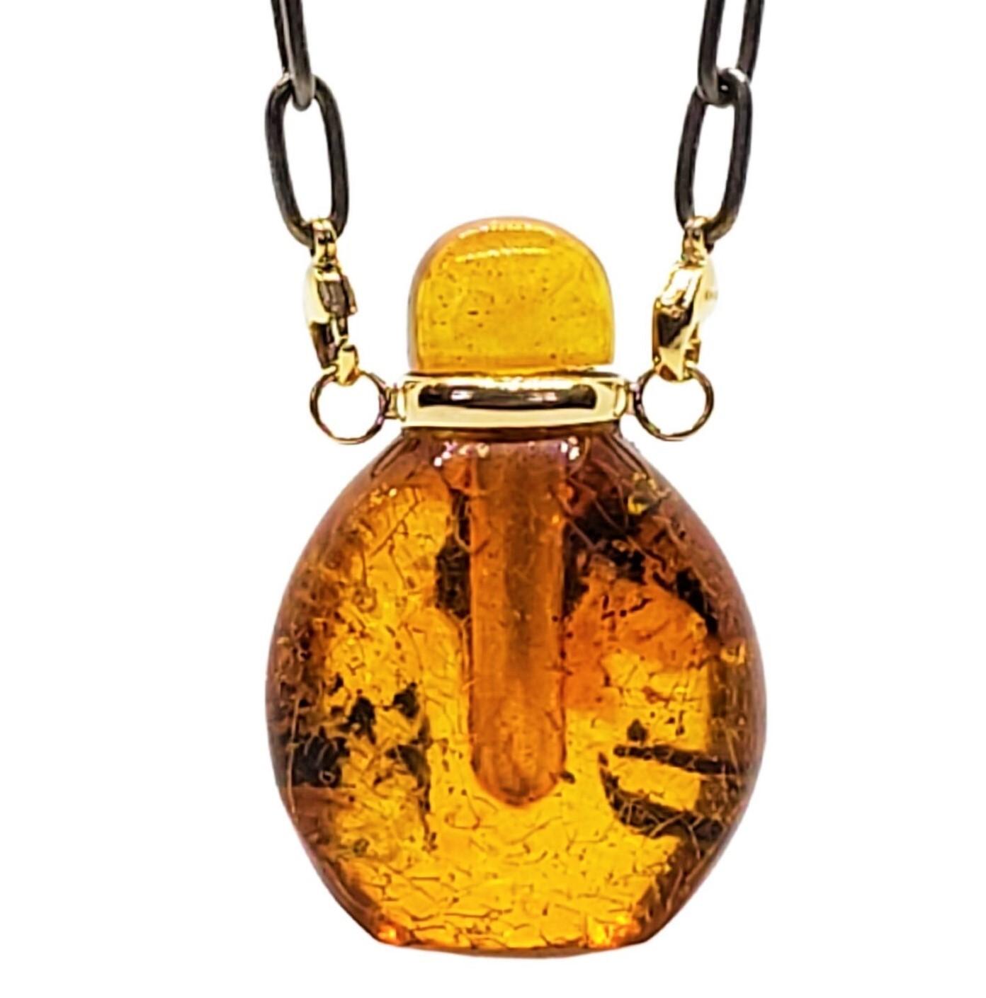 Amber especially from the Baltics, is always fascinating with no 2 pieces alike. A unique Perfume Bottle with an amber stopper could have a liquid filled into it. 
A handmade 14K yellow gold collar with loops east and west was made to suspend from