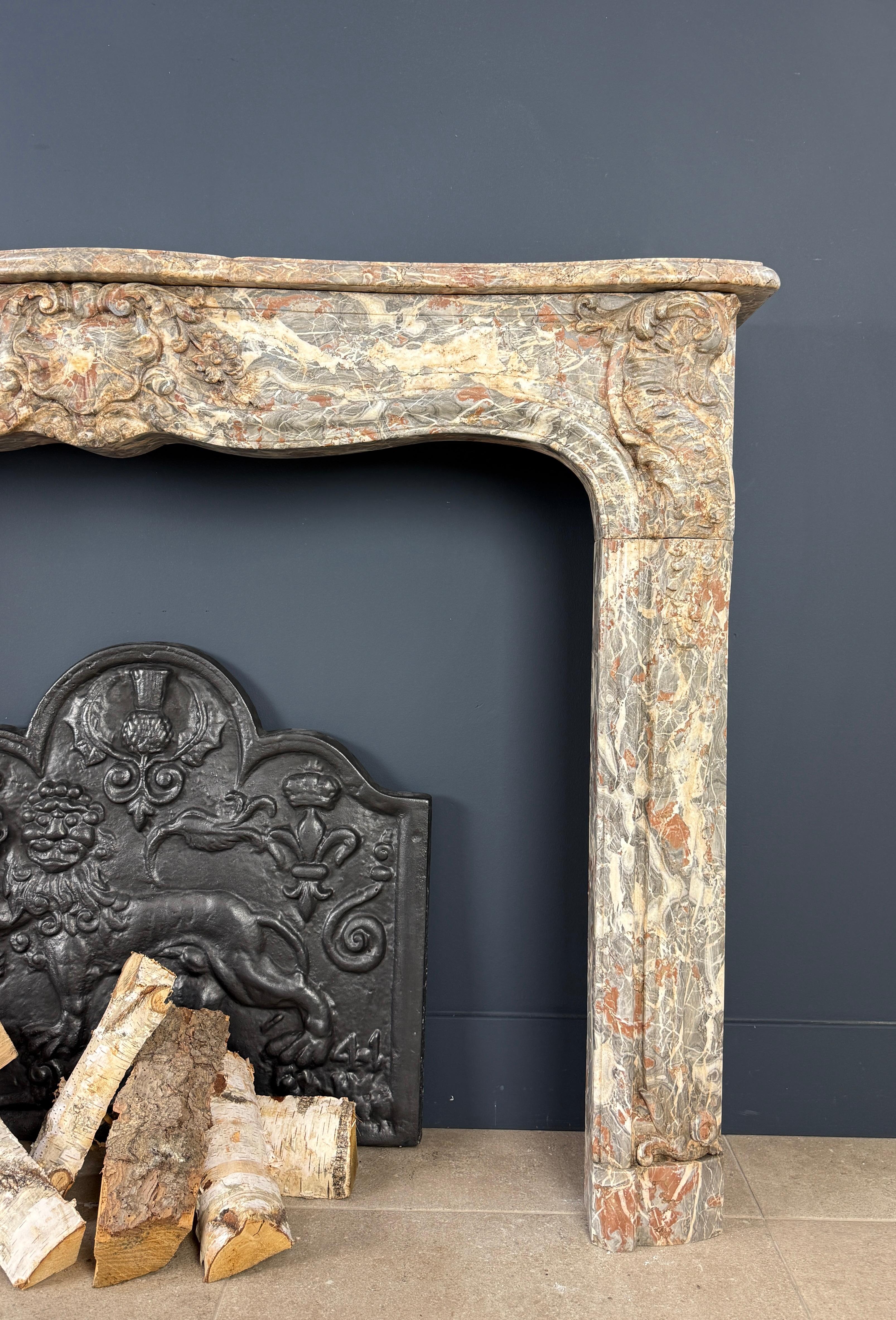 
This impressive antique fireplace, originating from Belgium and crafted around 1800, is a true masterpiece in natural stone. Made from a type of marble with an exceptionally rich color palette—ranging from deep reds to almost crystal-clear