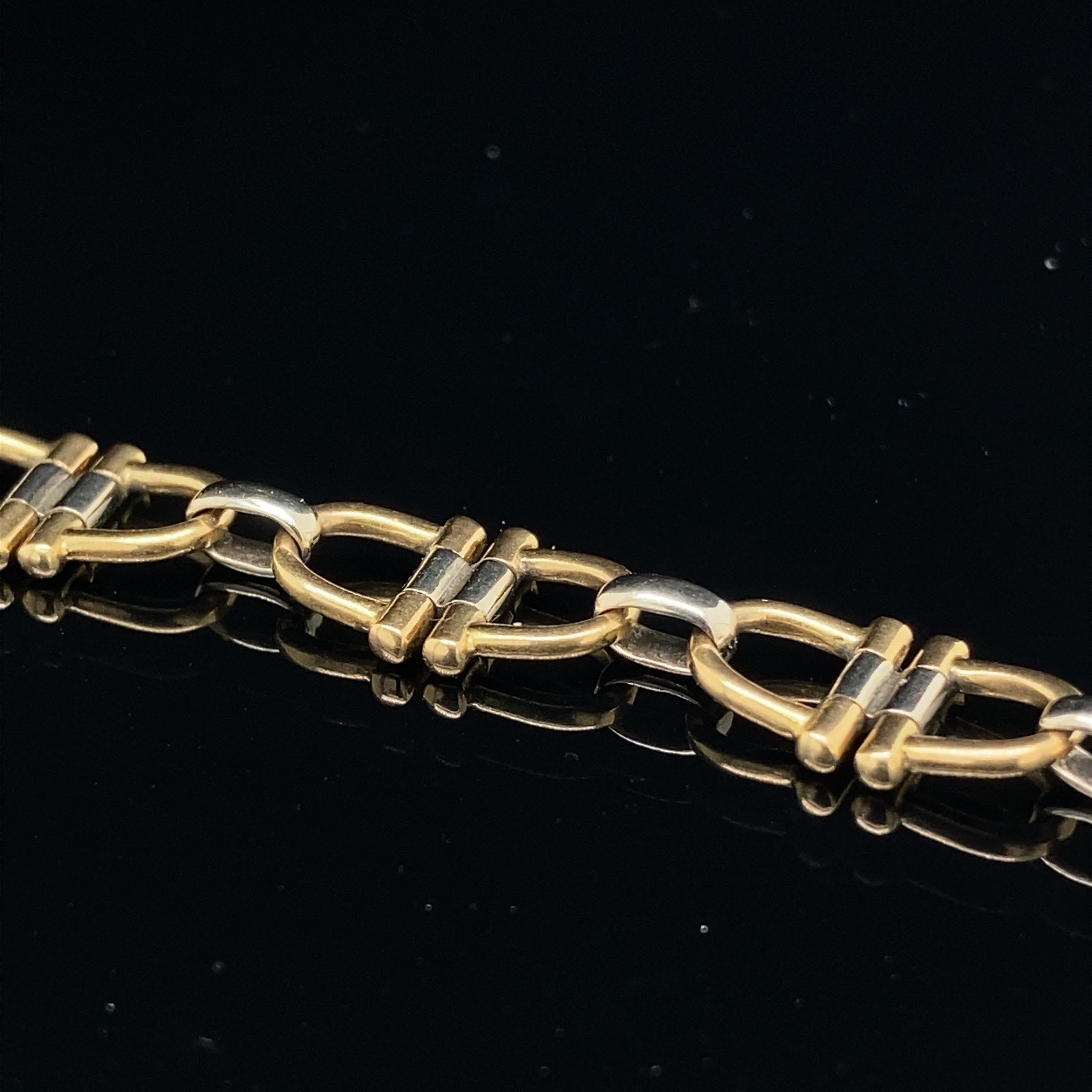 A delicate bicolour 18K gold Cartier bracelet, each element of stirrup shape. 
Signed Cartier and numbered 593765, marked 750.
The padlock clasp with additional safety closure.
19.5cm long
12.1g
With Cartier pouch and packaging.